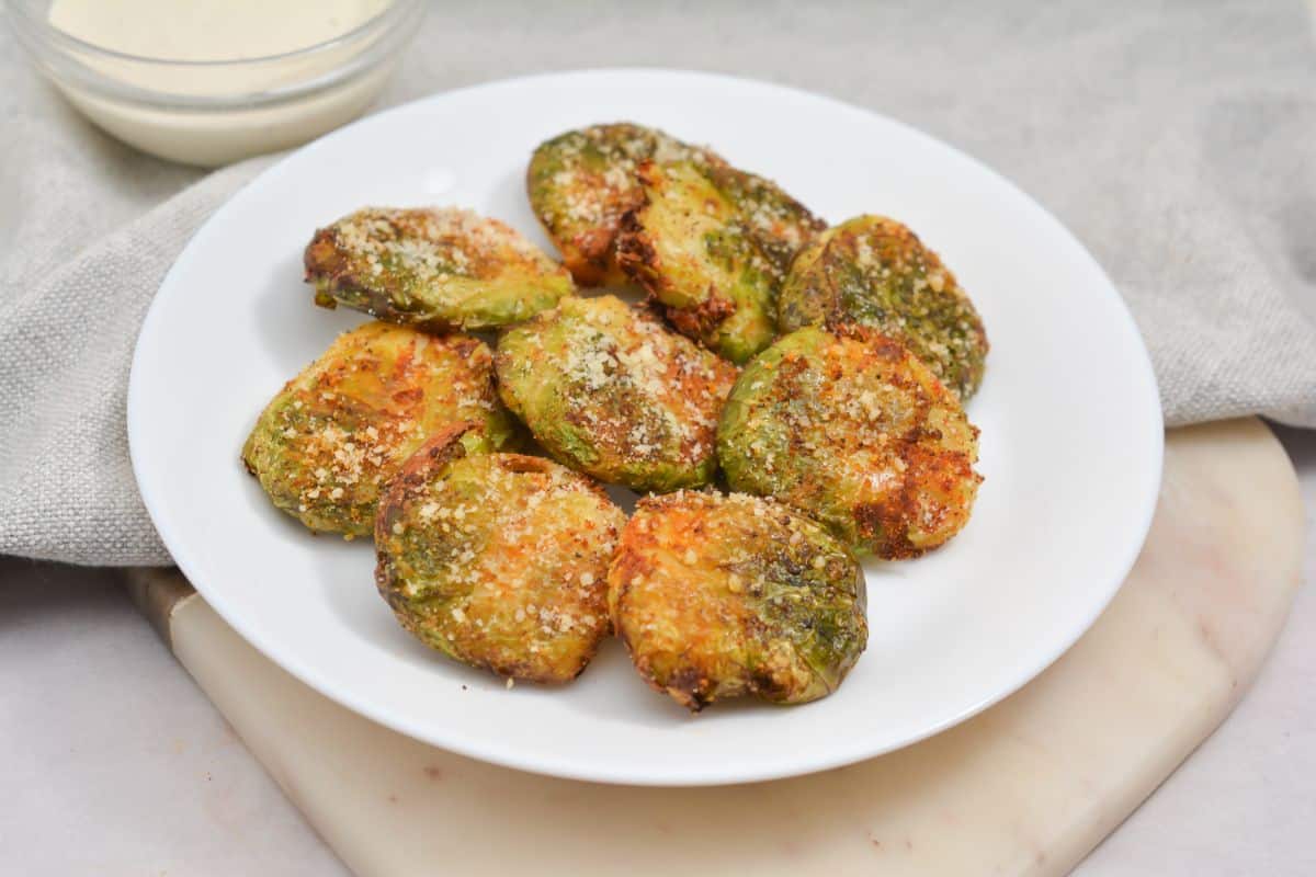 Keto Brussel Sprouts on a white plate and with dip on the side in a glass bowl