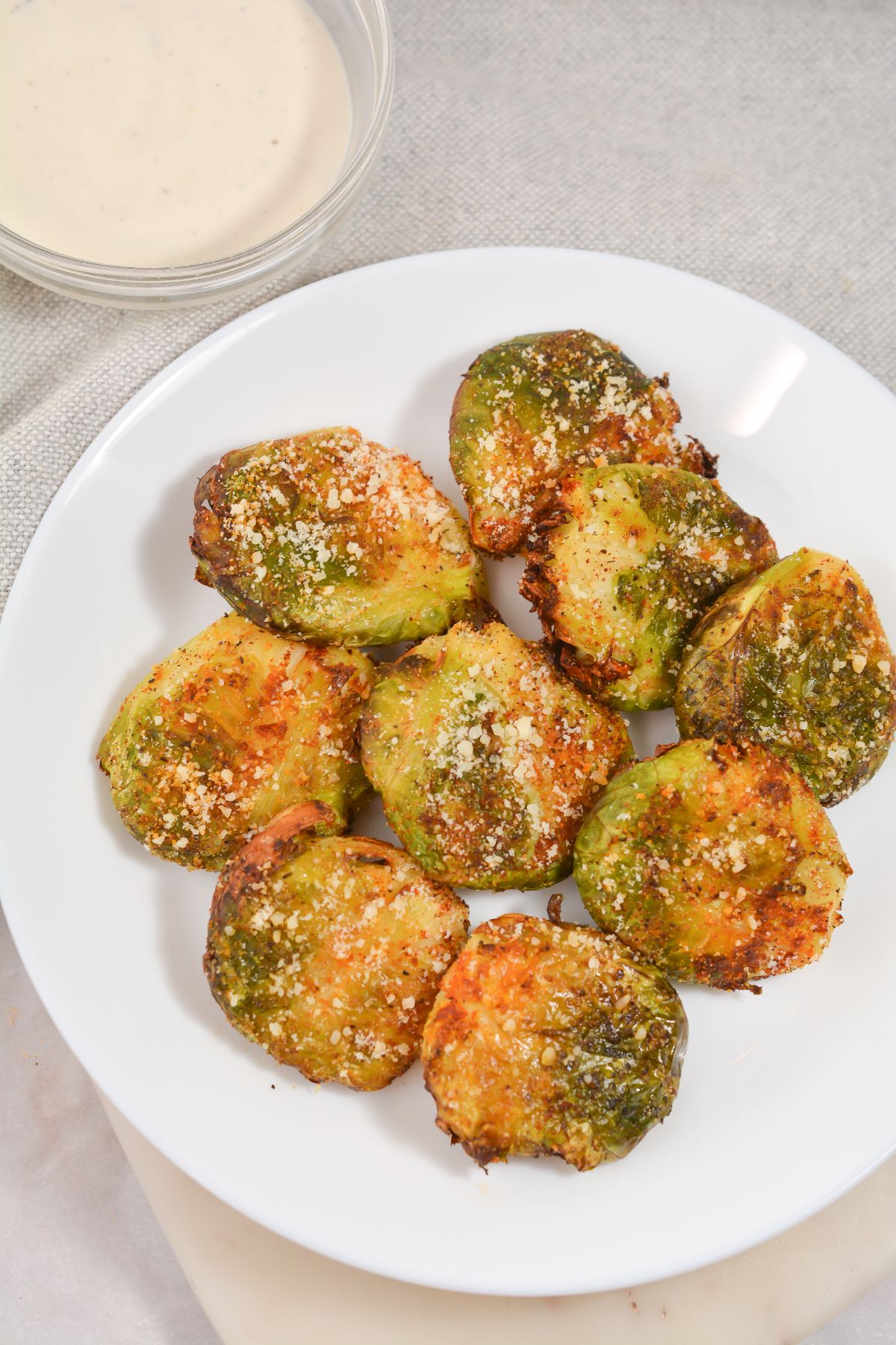Air Fryer Keto Brussel Sprouts on a white plate and with dip on the side in a glass bowl