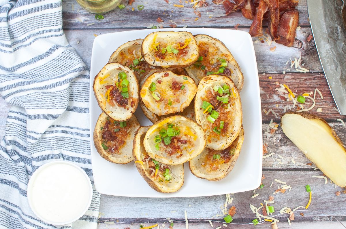 overhead view of Air Fryer Potato Skins on a plate with a  halved potato and ranch dressing on the side