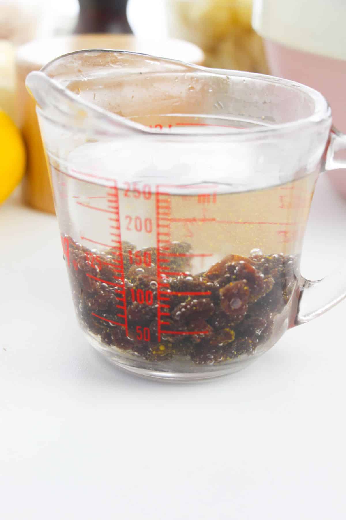 Measuring cup with hot water and raisins