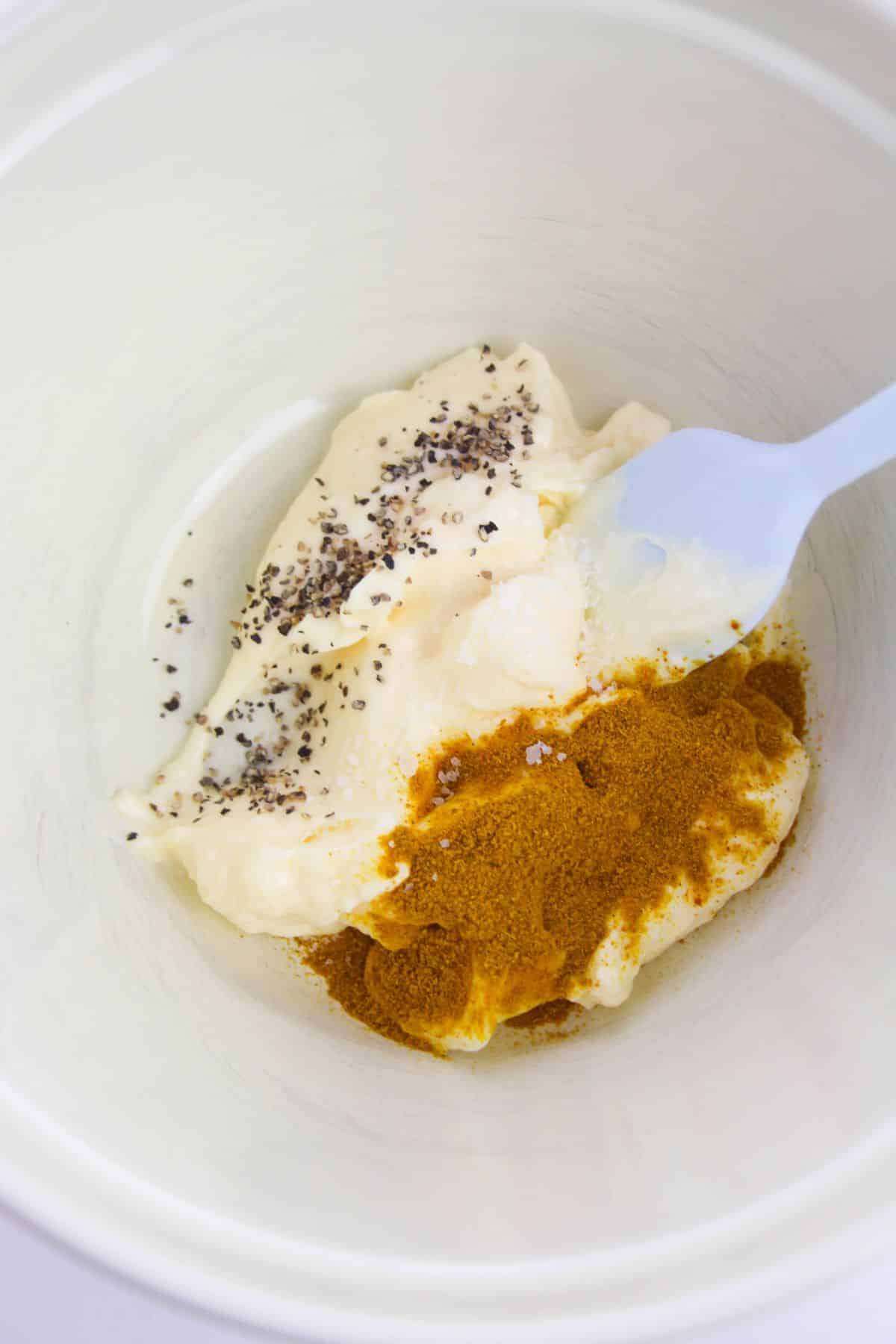 Mayonnaise, curry powder, salt, and pepper in a medium-sized bowl