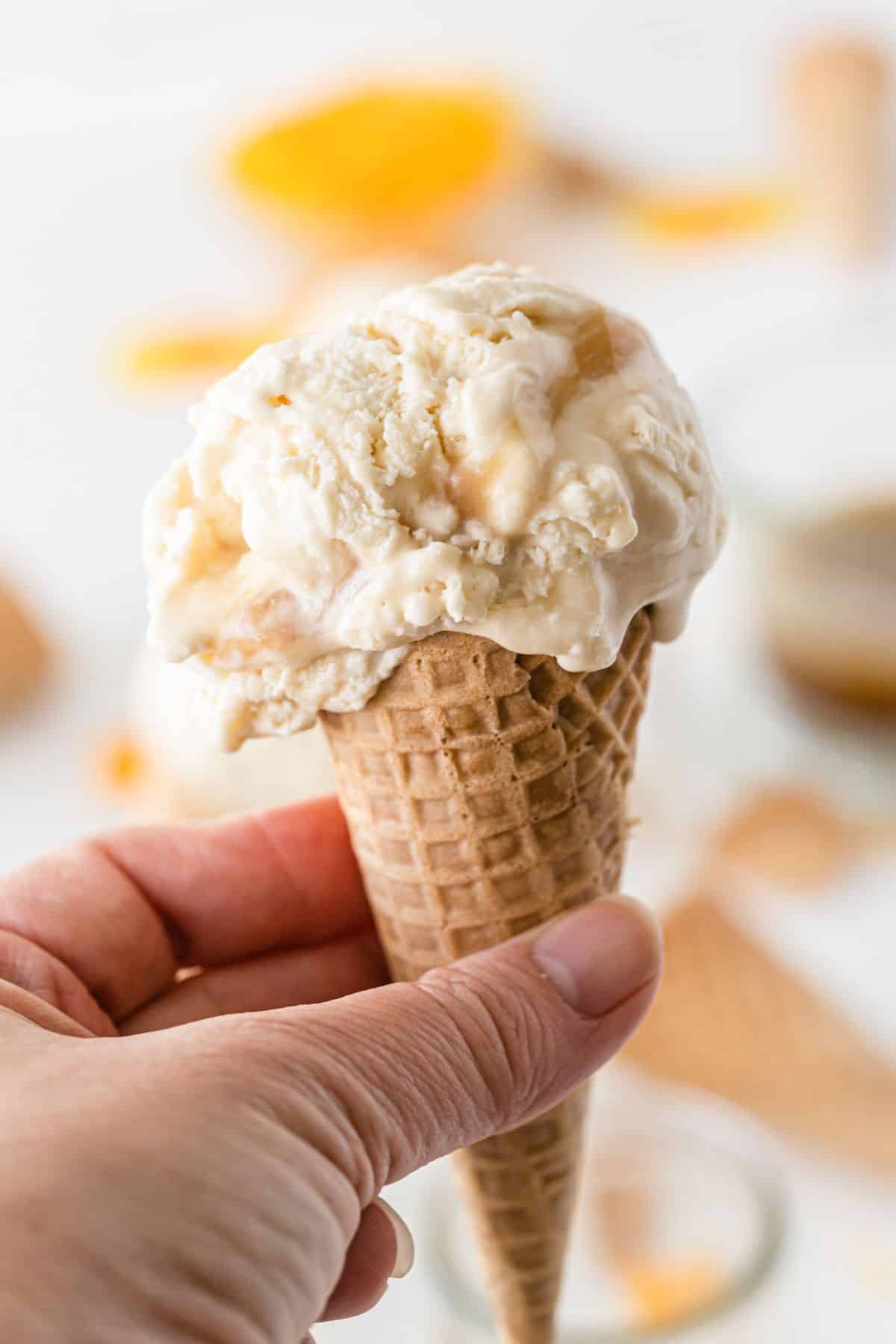 a closeup of a hand holding Butterbeer Ice Cream in a cone.