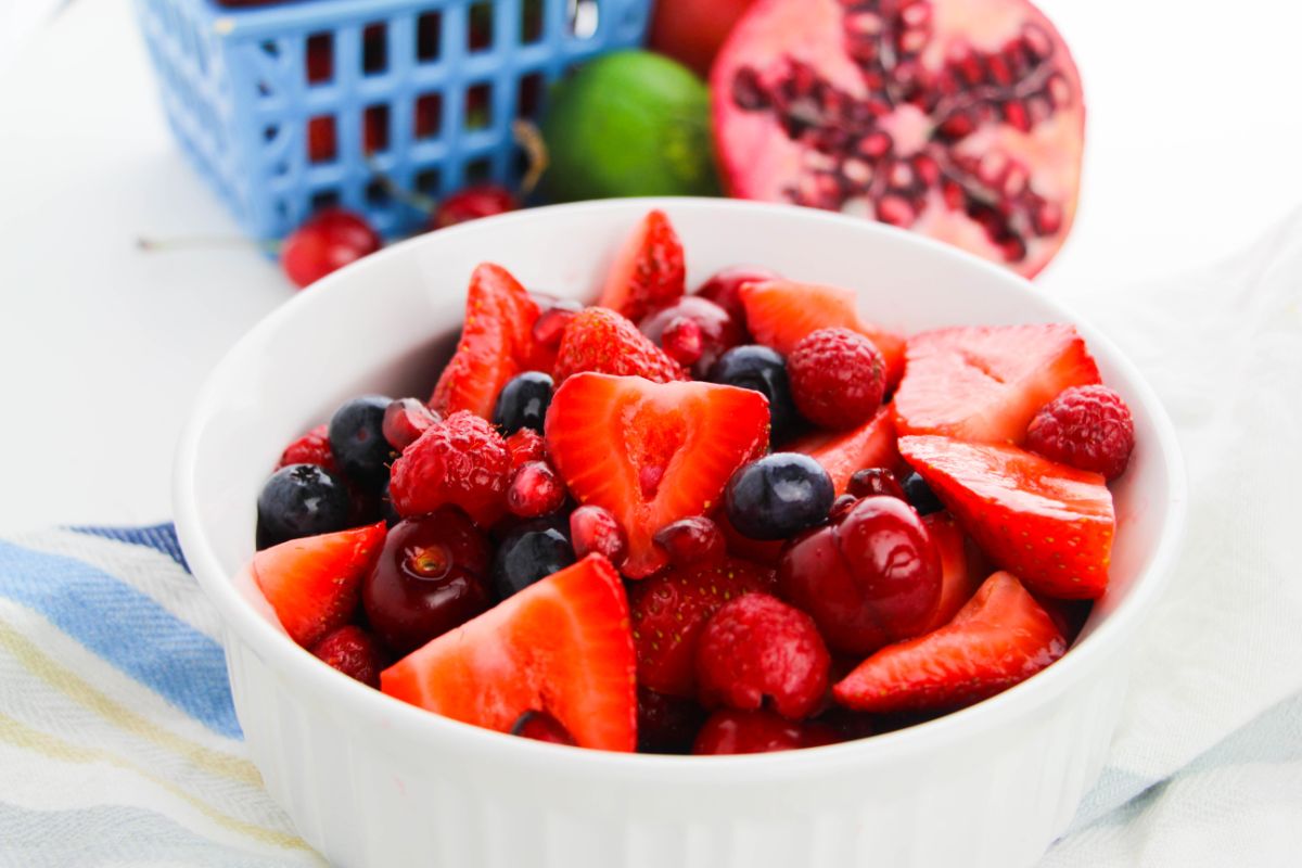 Fruit Berry Salad with Honey Lime Dressing in a bowl with more fruit on the side