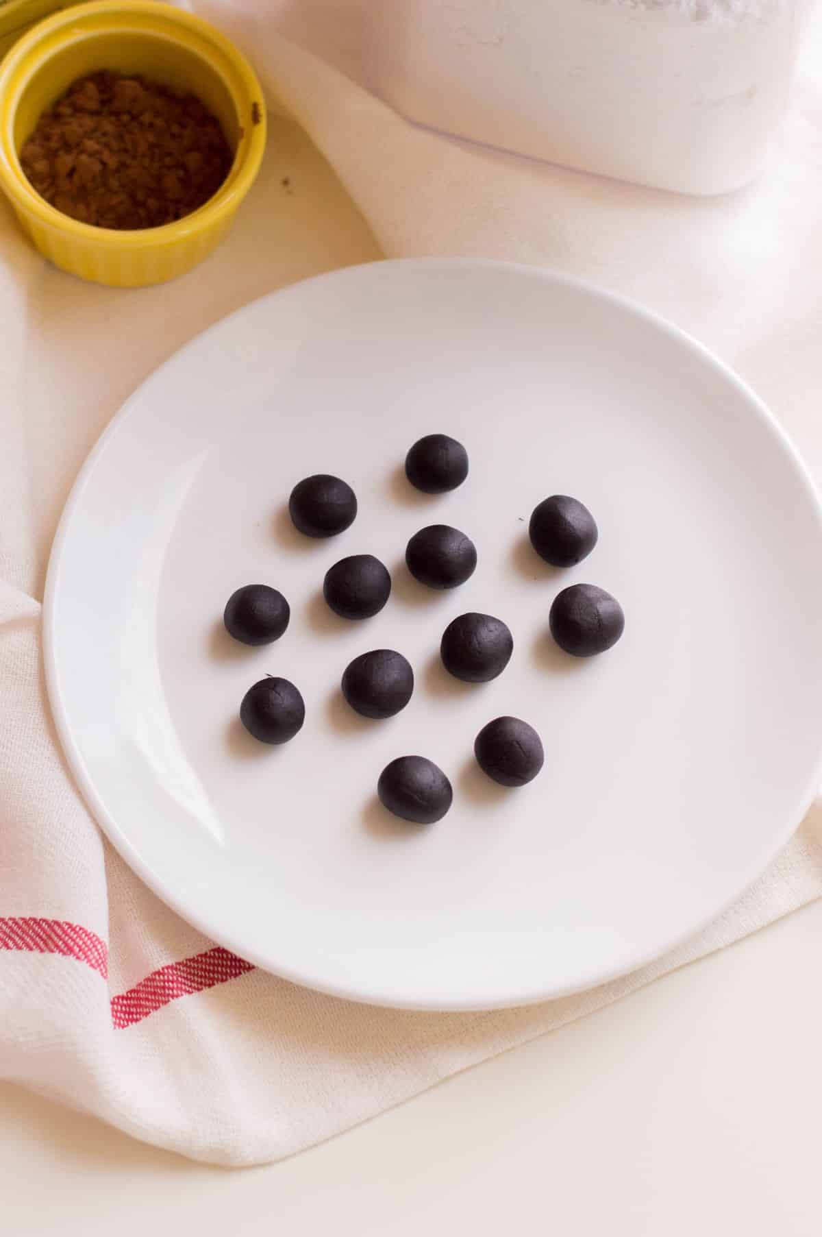 black fondant divided into ¾-inch spheres on a white plate