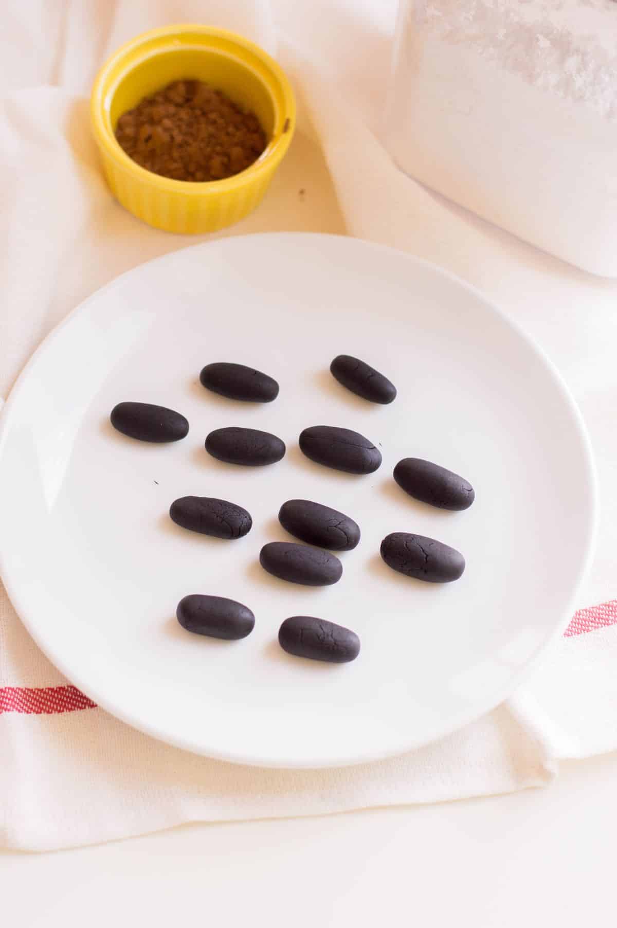 black fondant shaped into cylinders on a white plate
