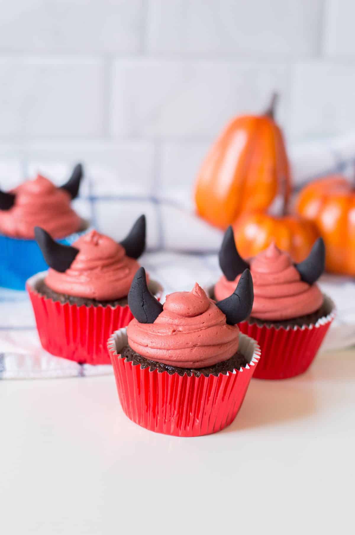 4 Halloween Devil Cupcakes with pumpkins in the background