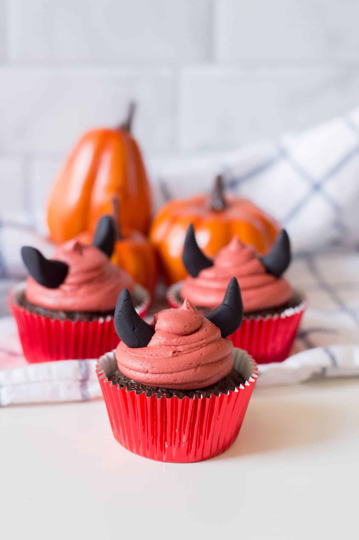 3 Halloween Devil Cupcakes with pumpkins in the background