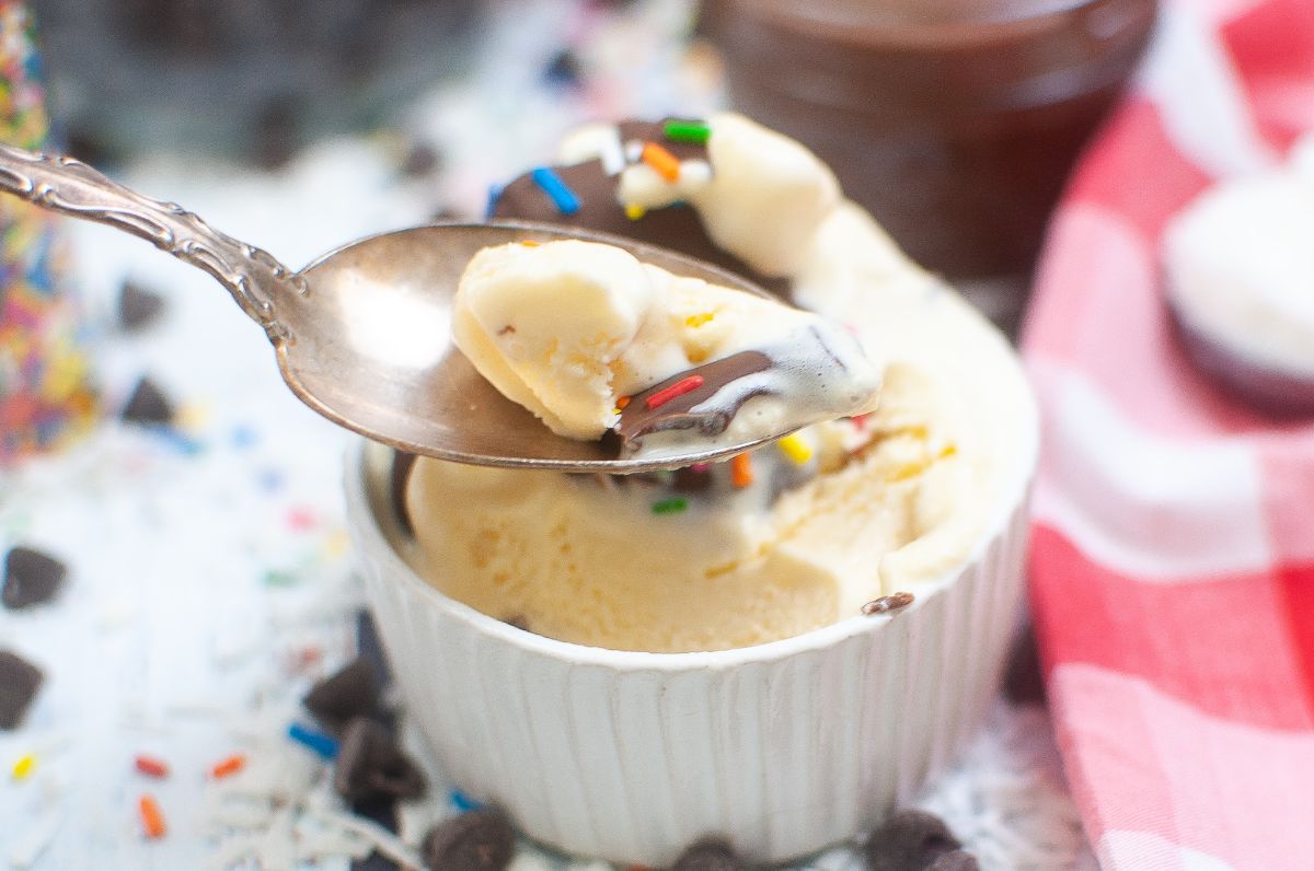 a spoon with ice cream and ice magic on it next to Ice cream in a small bowl with homemade ice magic chocolate sauce