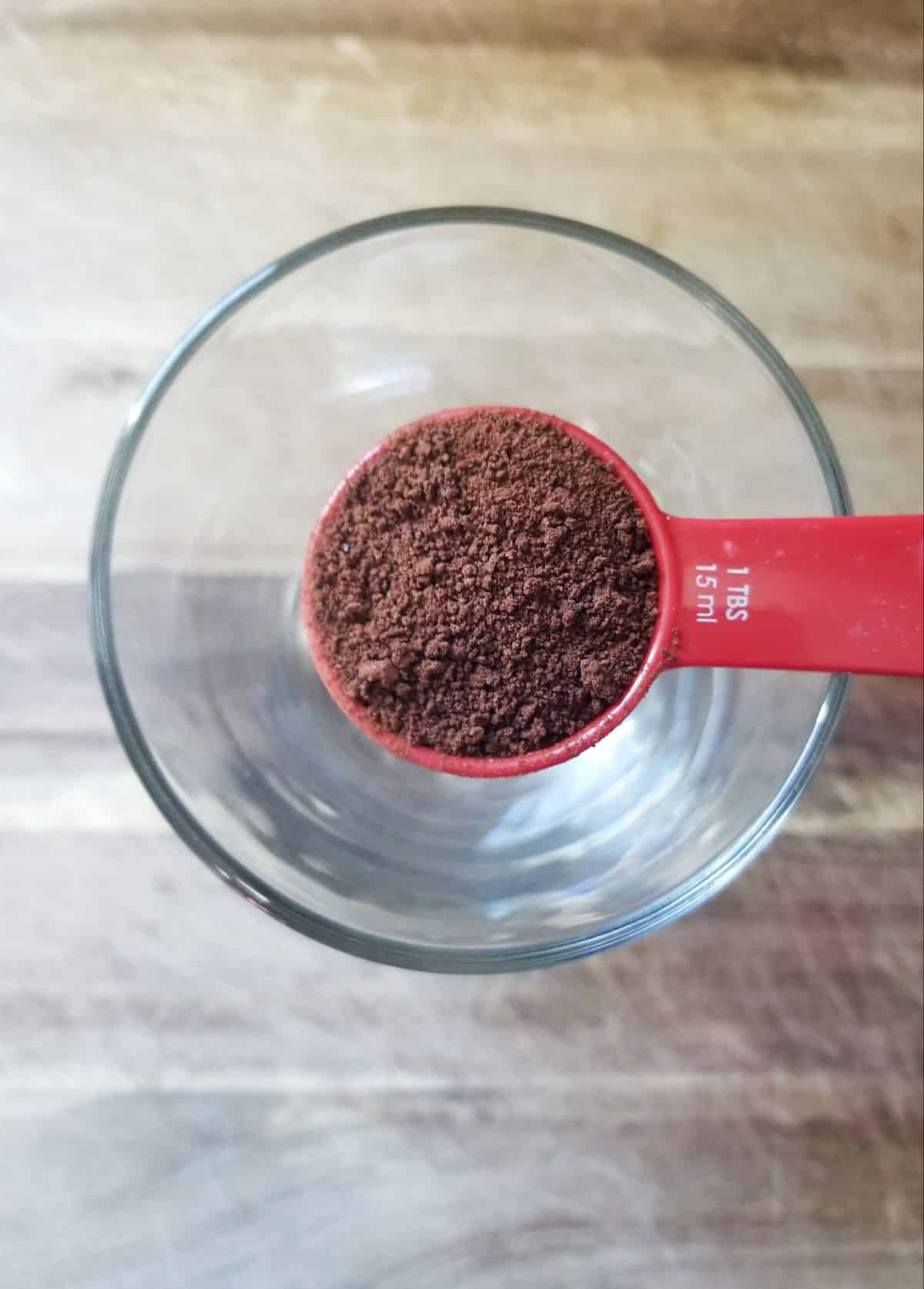 instant coffee in a tablespoon above a glass