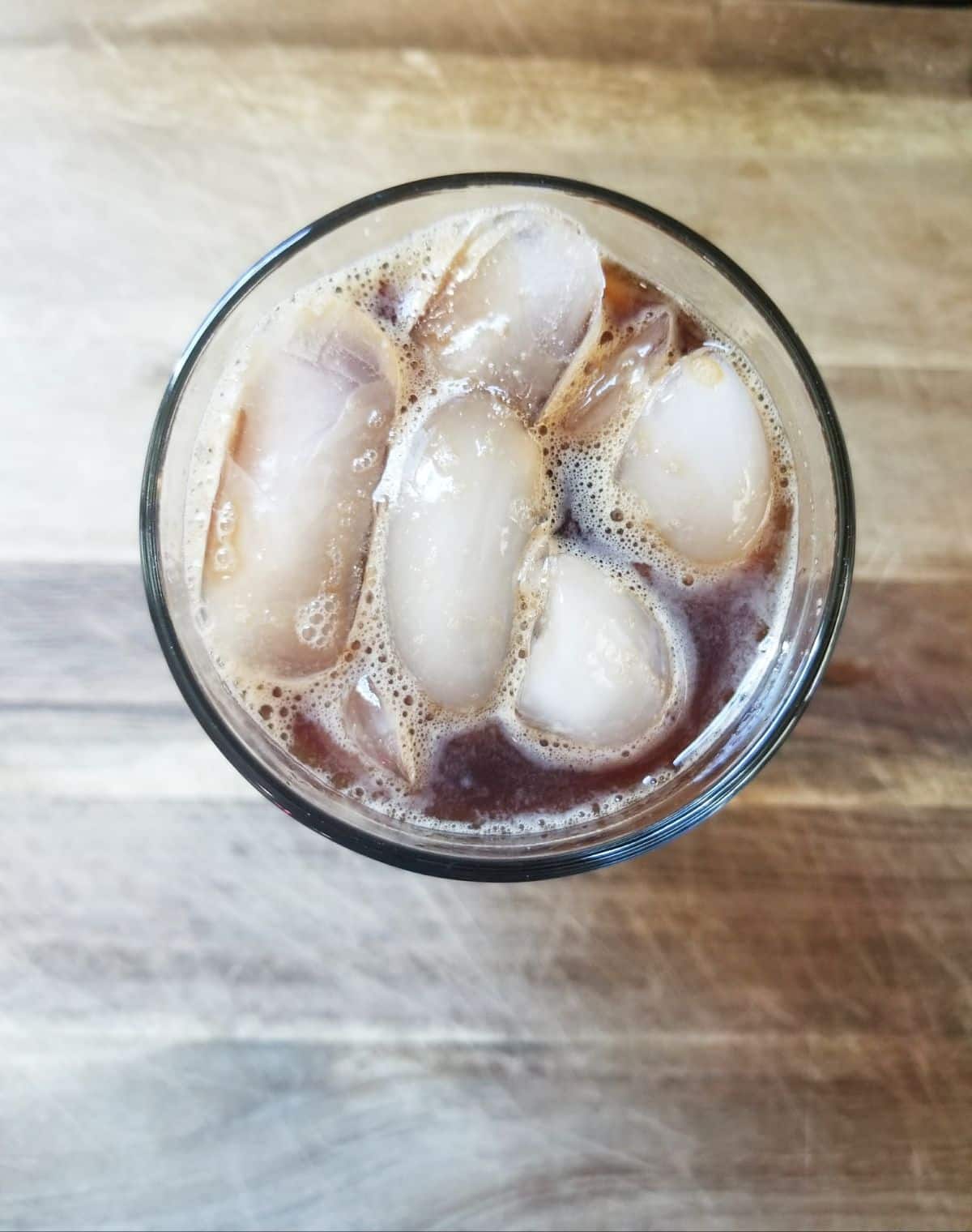 overhead view of  ice, sugar, and creamer in a glass of coffee
