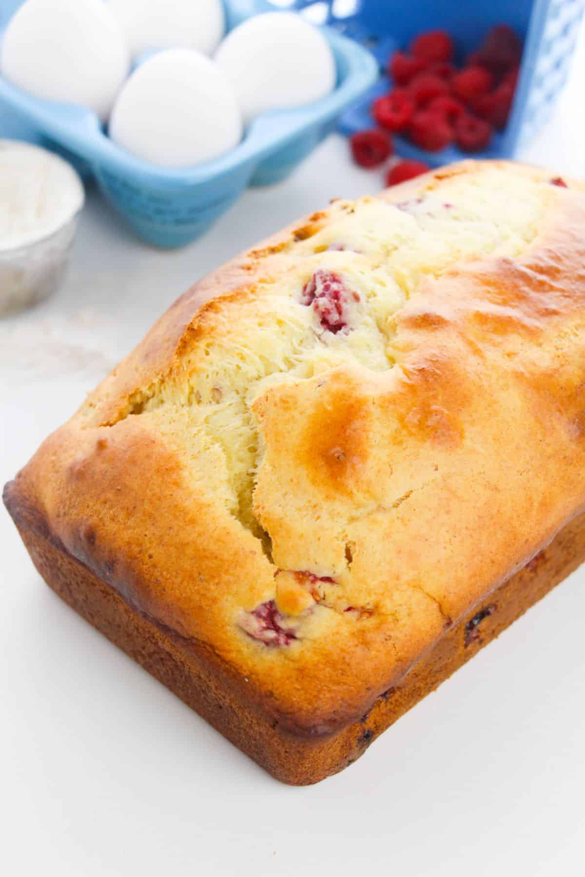Lemon Raspberry Loaf with flour, egg and raspberries on the side
