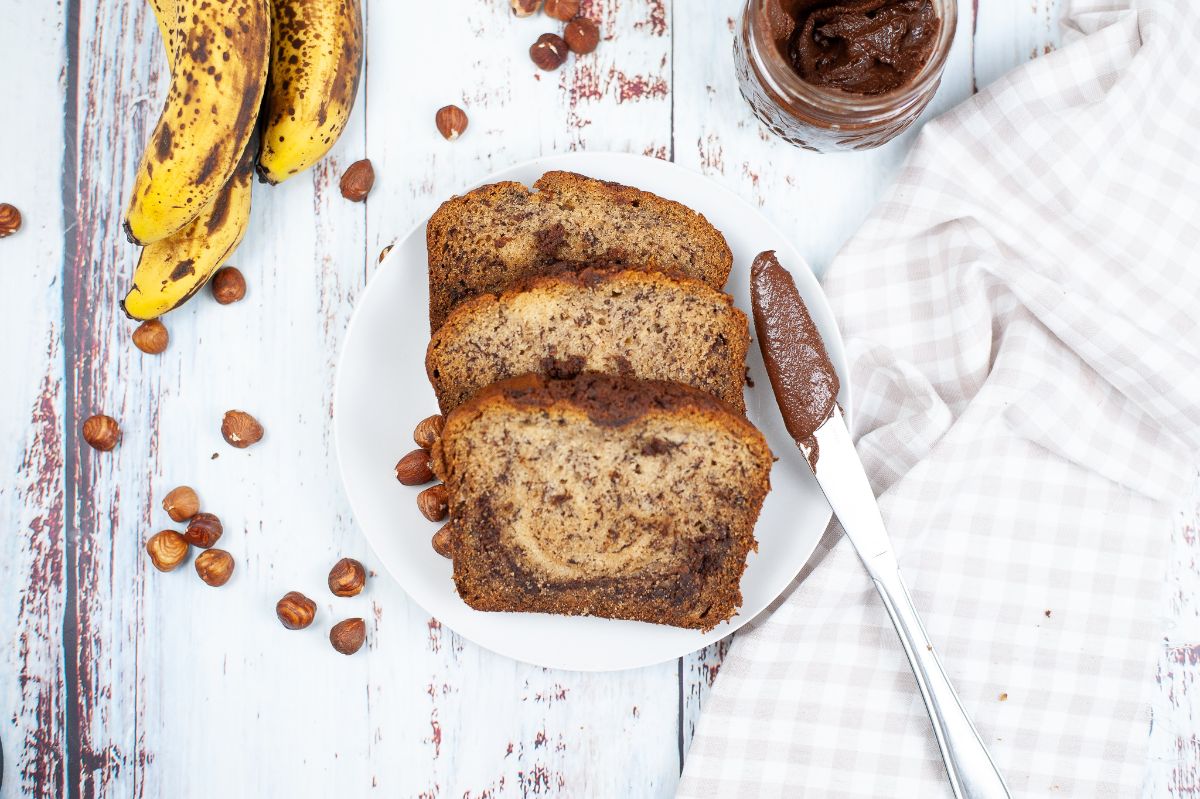 sliced Nutella Banana Bread on a plate with banana, knife and Nutella on the side