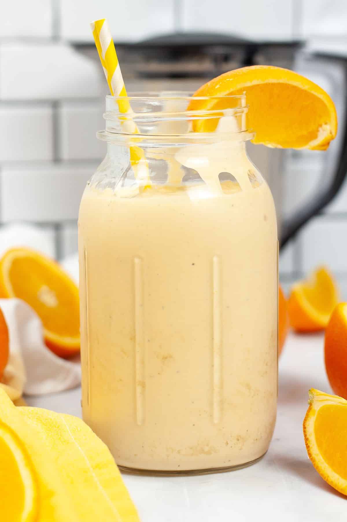 Orange Milkshake in a jar with a straw and orange slice