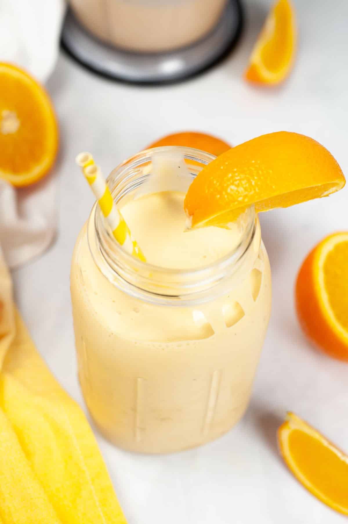 Orange Milkshake in a jar with a straw and orange slice