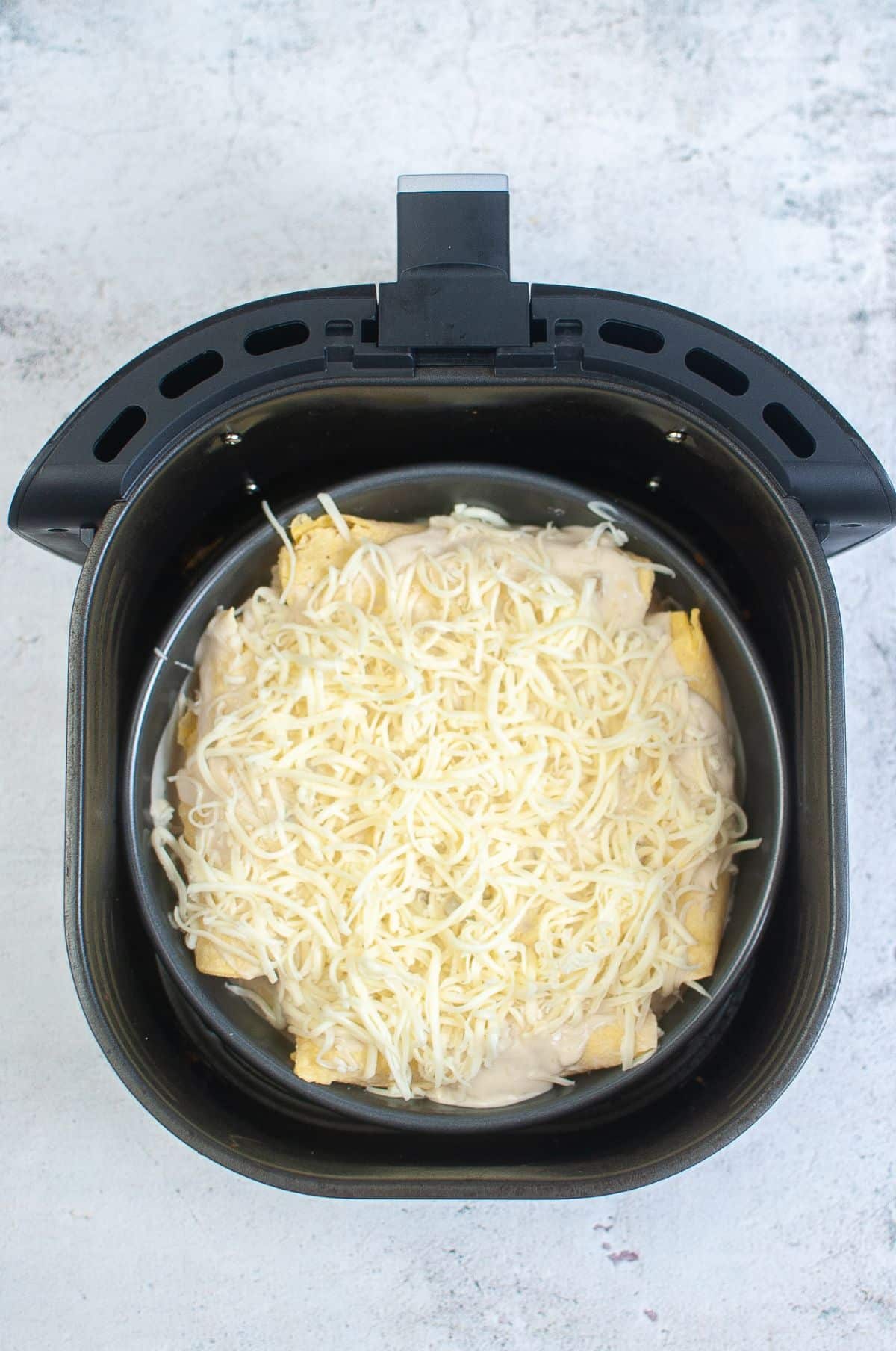 Rolled tortillas with cheese and green enchilada sauce in Air Fryer.