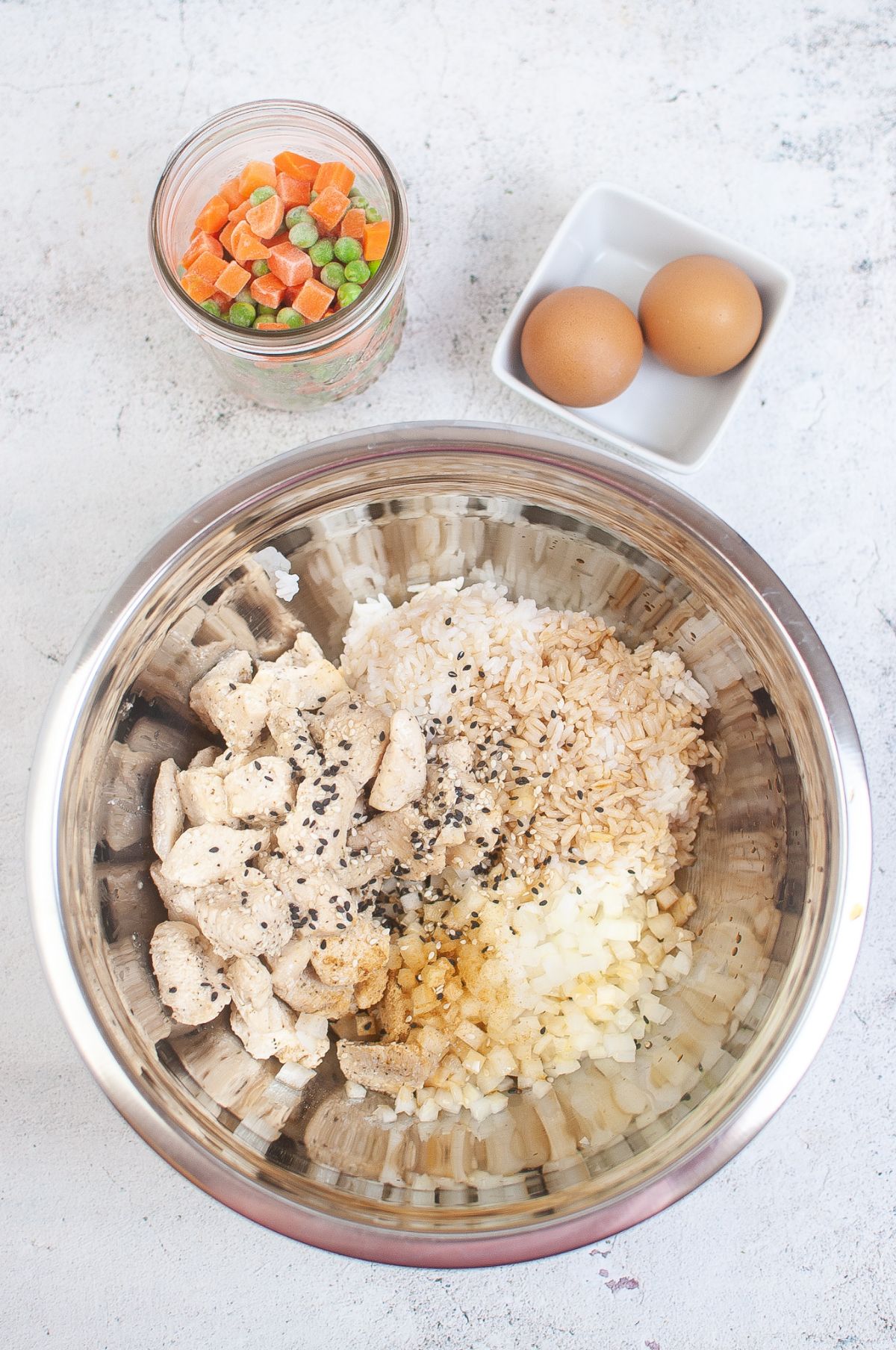 Rice, onion, soy sauce, sesame seeds, sesame oil, ginger, and chicken in a large bowl.