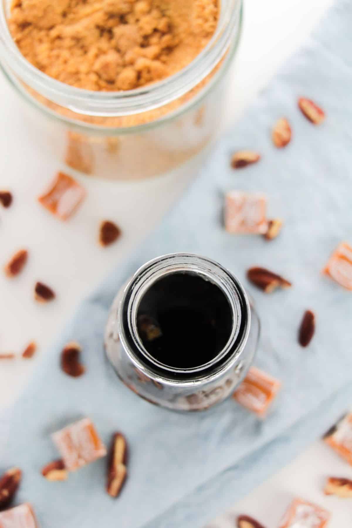 overhead view of Caramel Pecan Syrup in a bottle with brown sugar and pecans on the side.