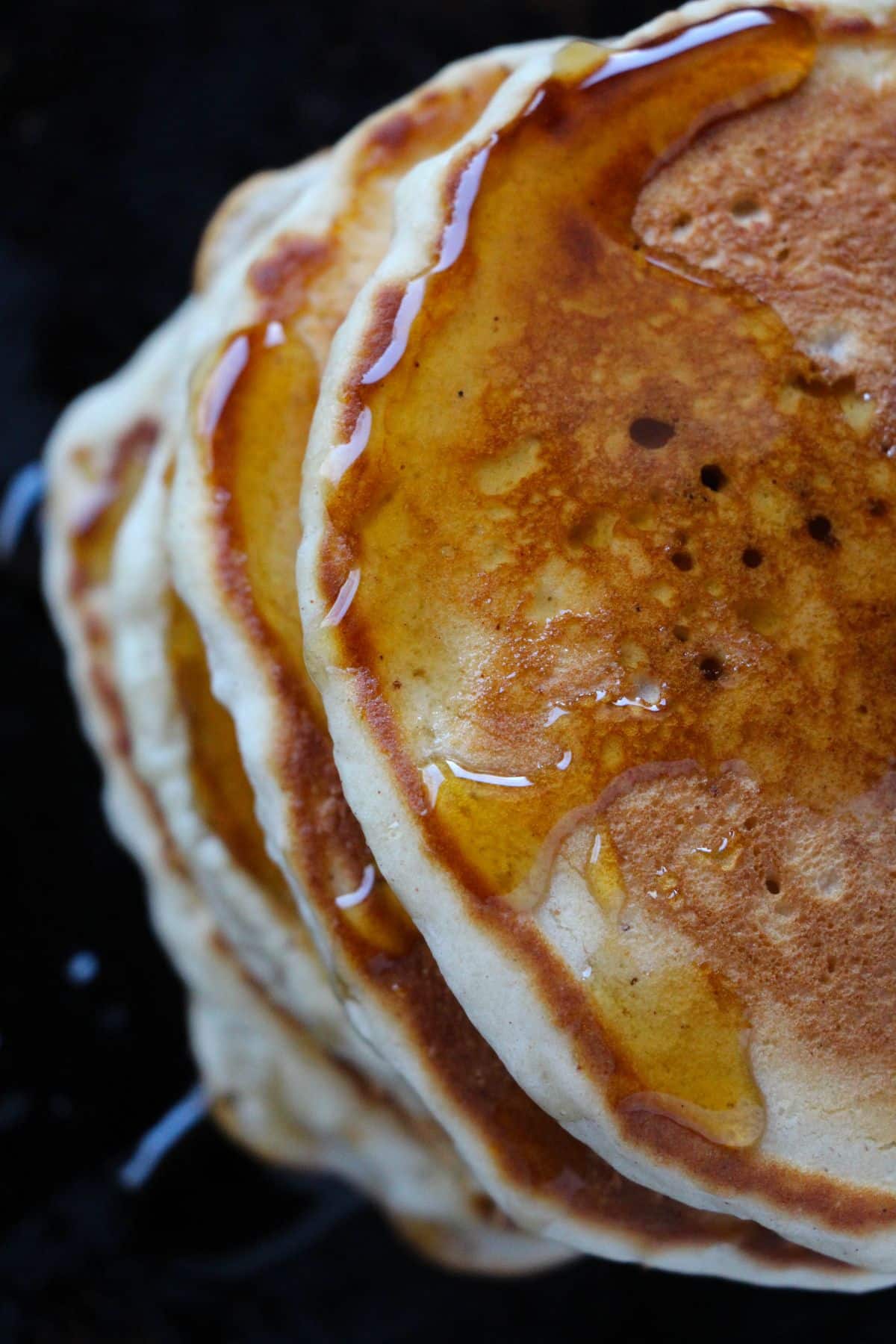 closeup of a stack of Eggnog Pancakes topped with maple syrup.