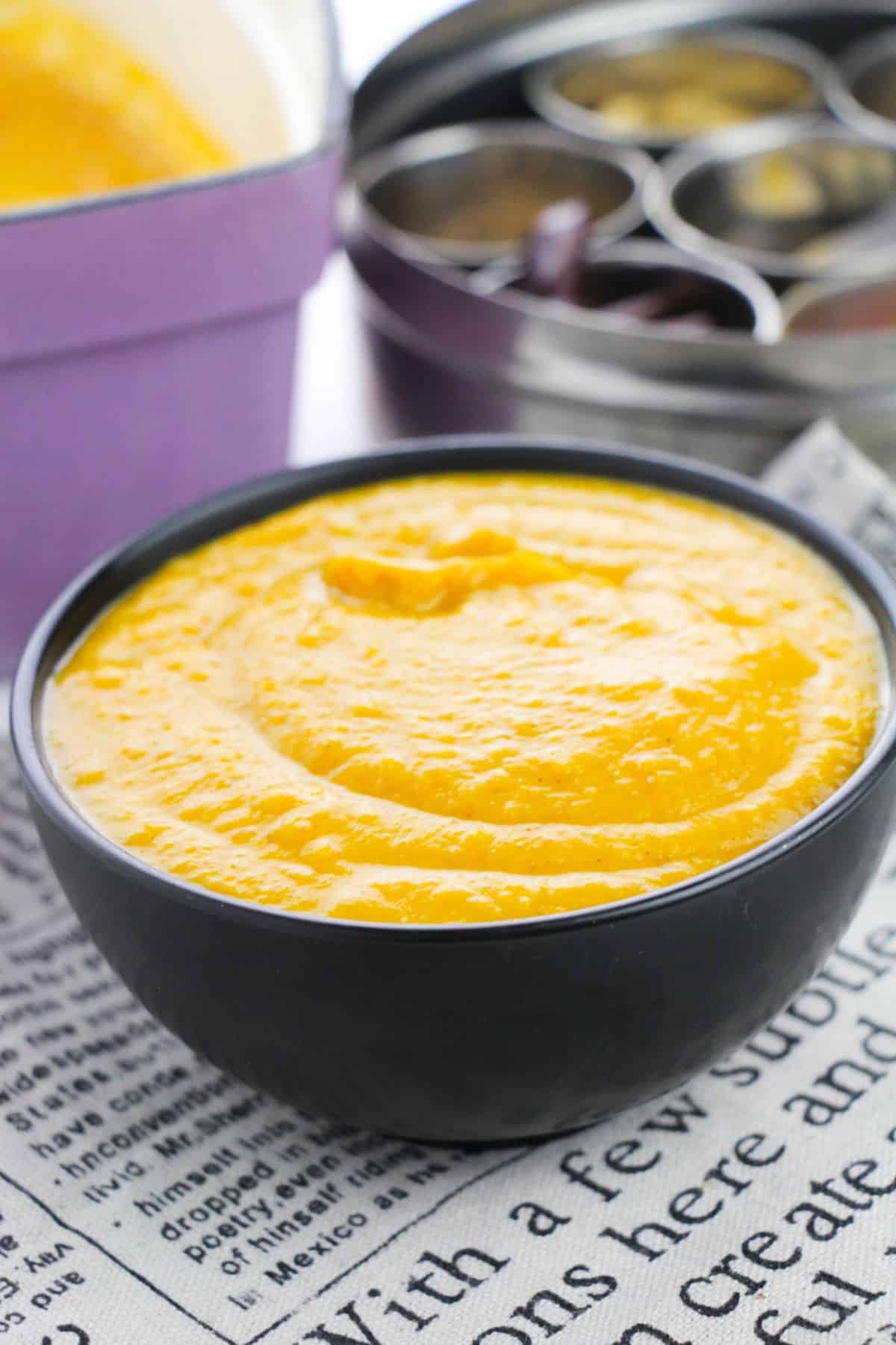 Pumpkin Butternut Squash Soup in a serving bowl with spices on the side.