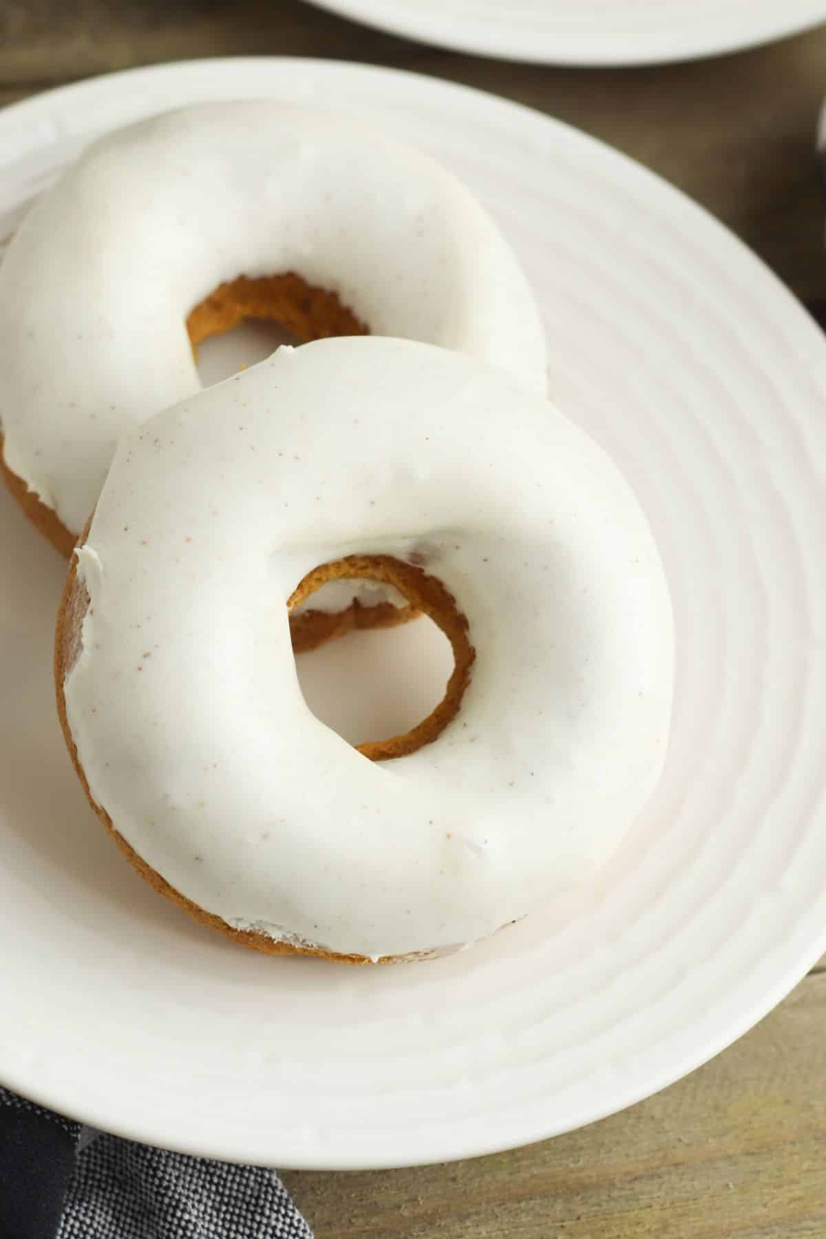 a closeup of two Pumpkin Cake Doughnuts on a white plate
