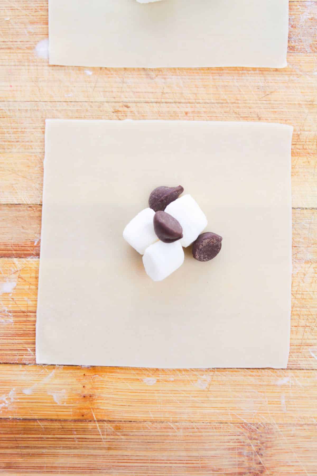 Wonton wrapper with chocolate chips and marshmallows on top.