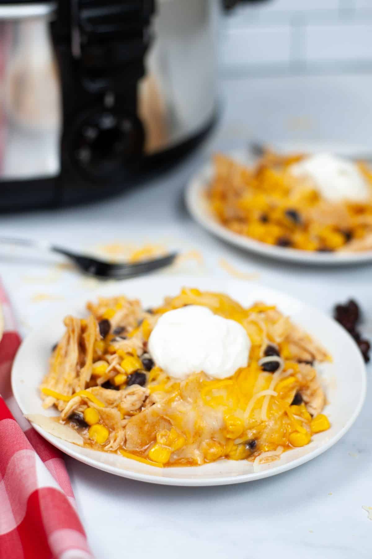 Chicken Slow Cooker Enchiladas on a serving plate, garnished with sour cream.
