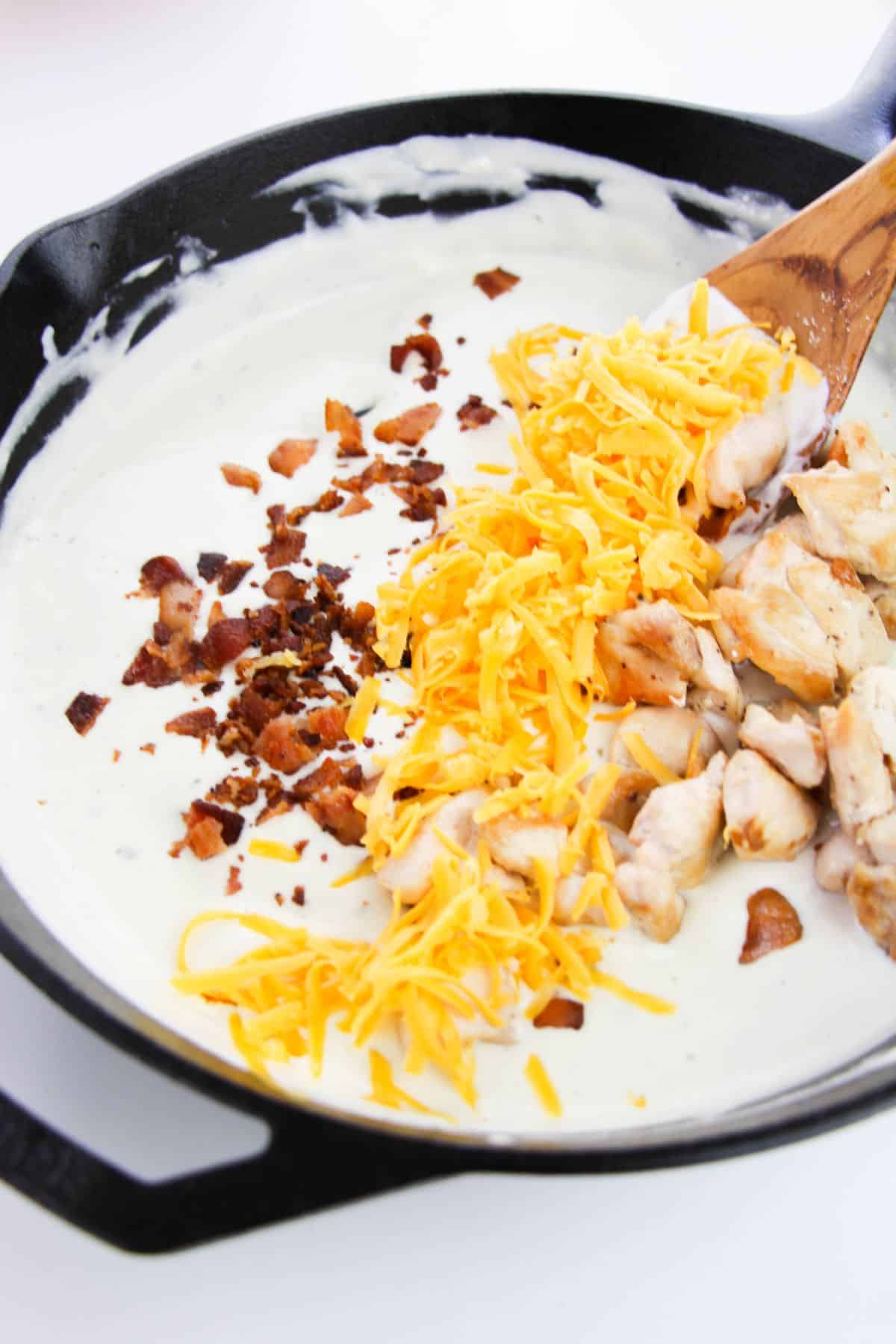 The cheese, bacon, and chicken are added to the sauce mixture.