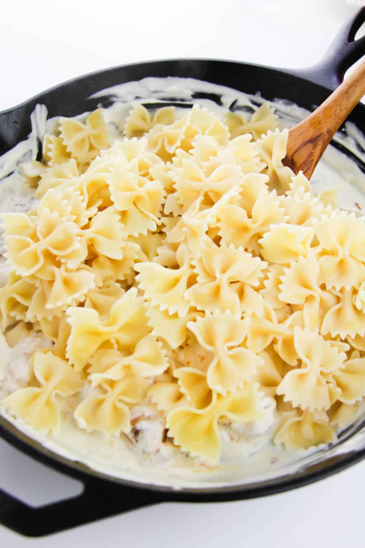 The bowtie pasta is added to the sauce mixture.