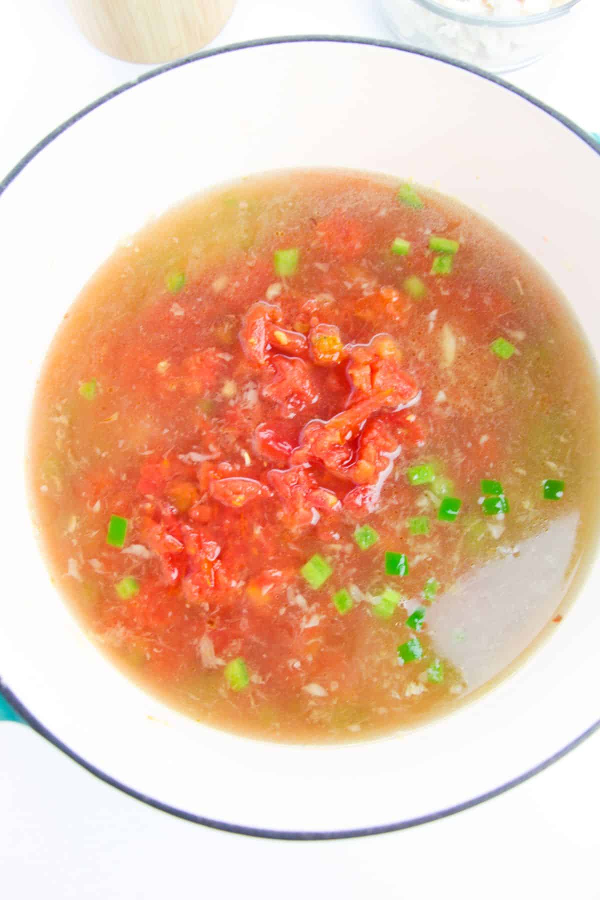 The chicken broth, tomatoes, and Rotel are added to the soup pot.