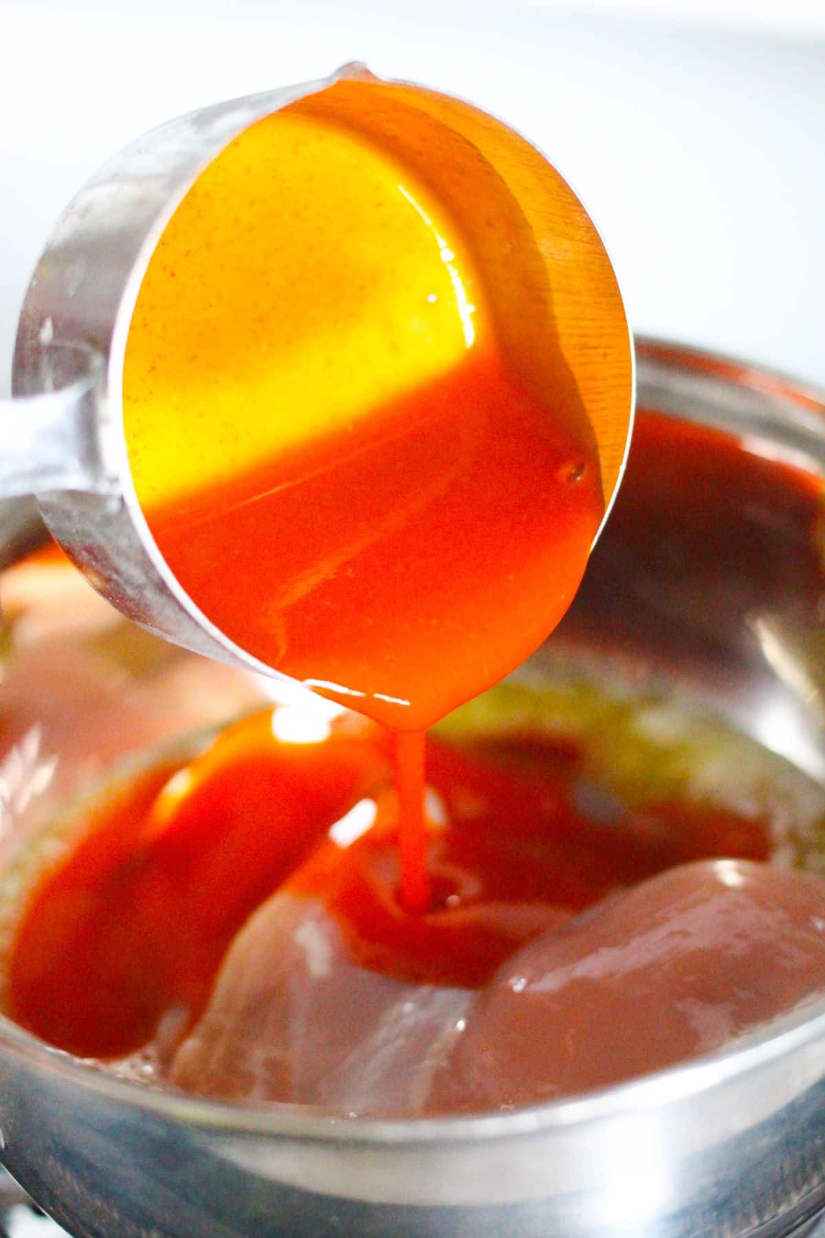 In a small pan, the buffalo sauce is being added to the chicken breasts.