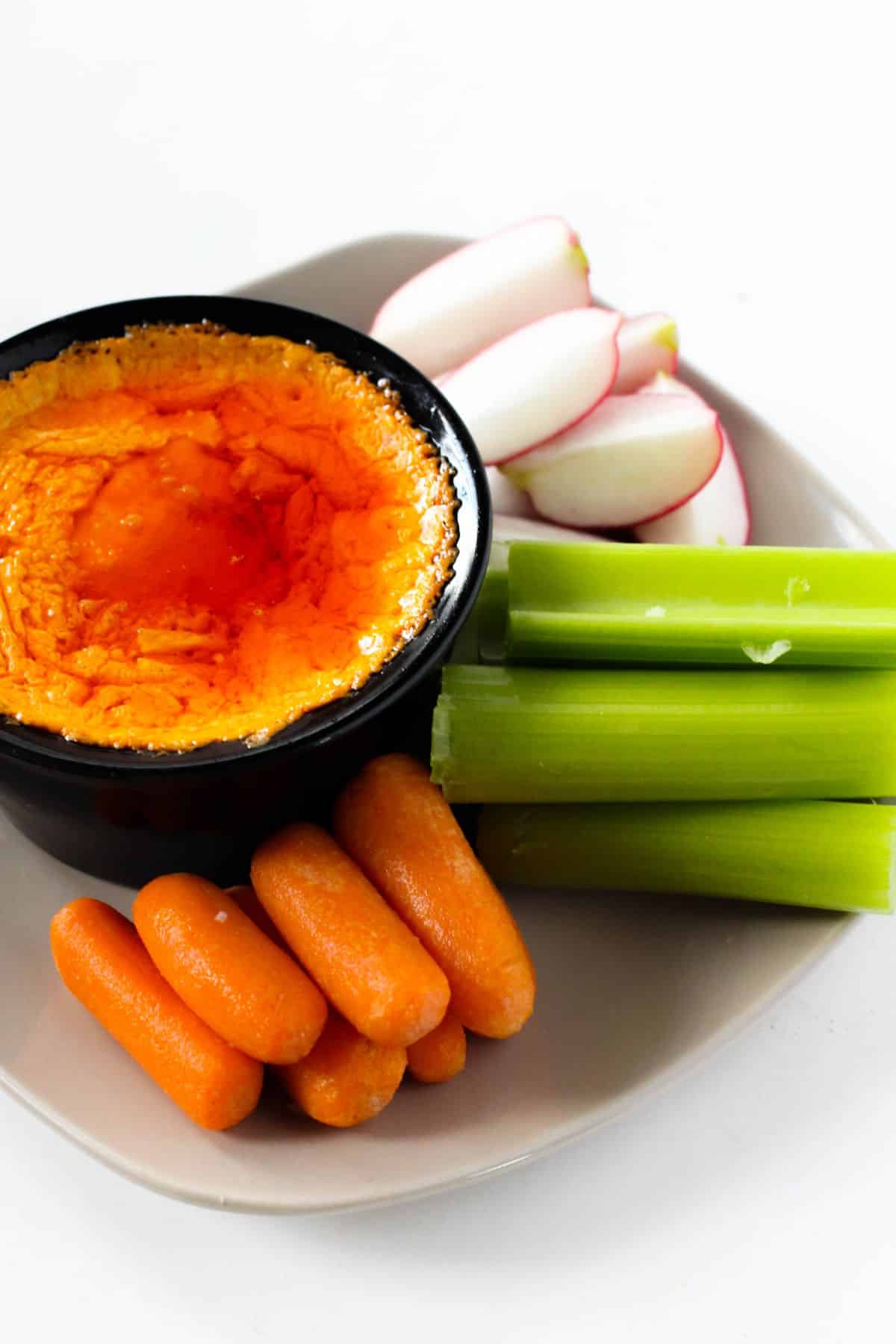 Slow Cooker Buffalo Chicken Dip in a serving bowl with vegetables on the side.