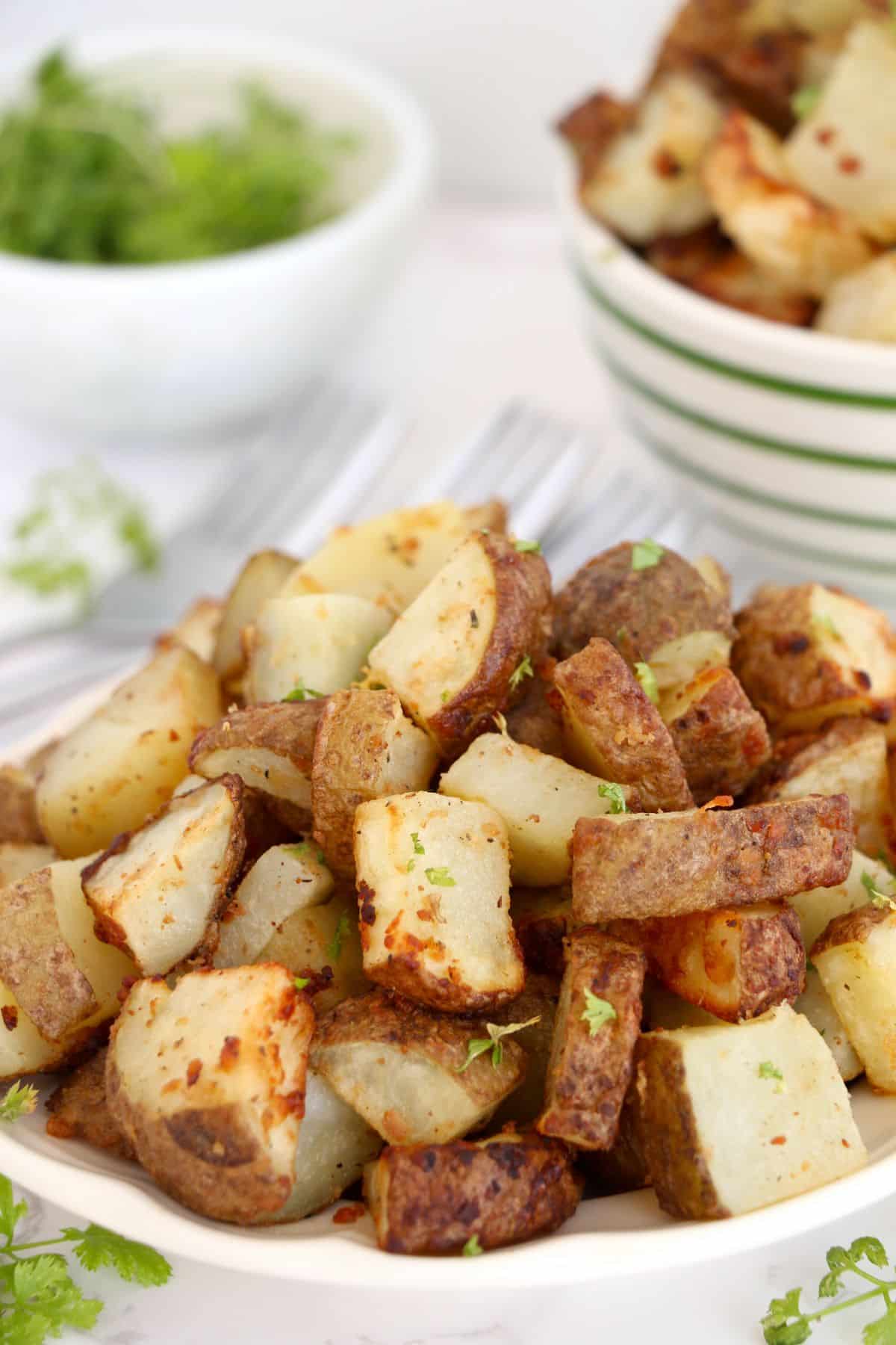 Air Fryer Diced Potatoes on a serving plate, garnished with parsley.
