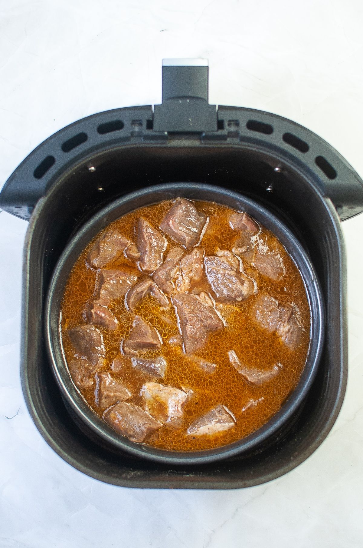 Beef and marinade in a pan in the air fryer.