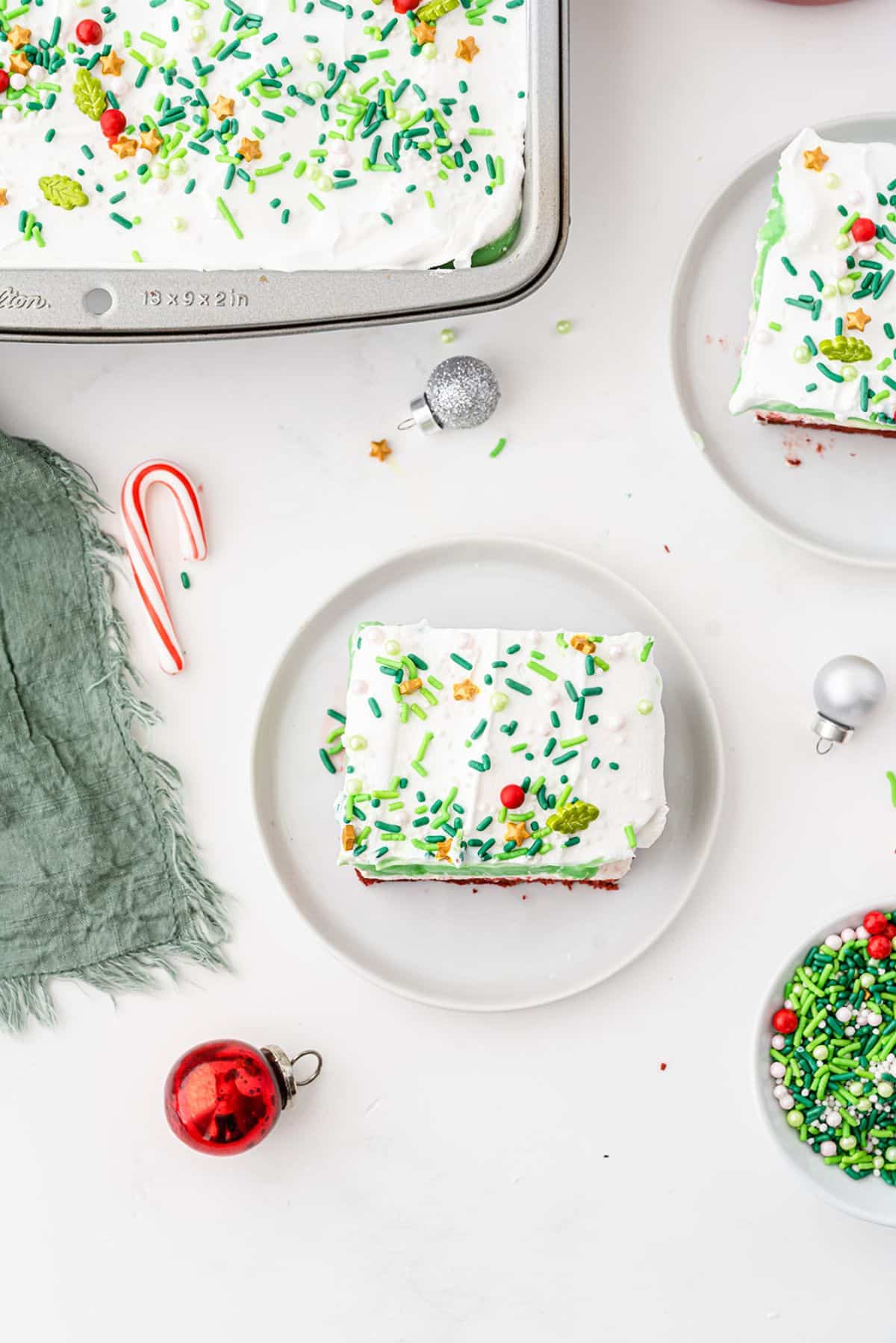 Slice of Christmas Dessert Lasagna on a serving plate with candy canes and other decorations scattered around.