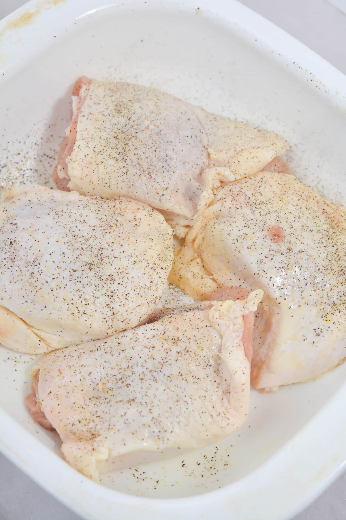 Chicken in the baking dish seasoned with pepper.