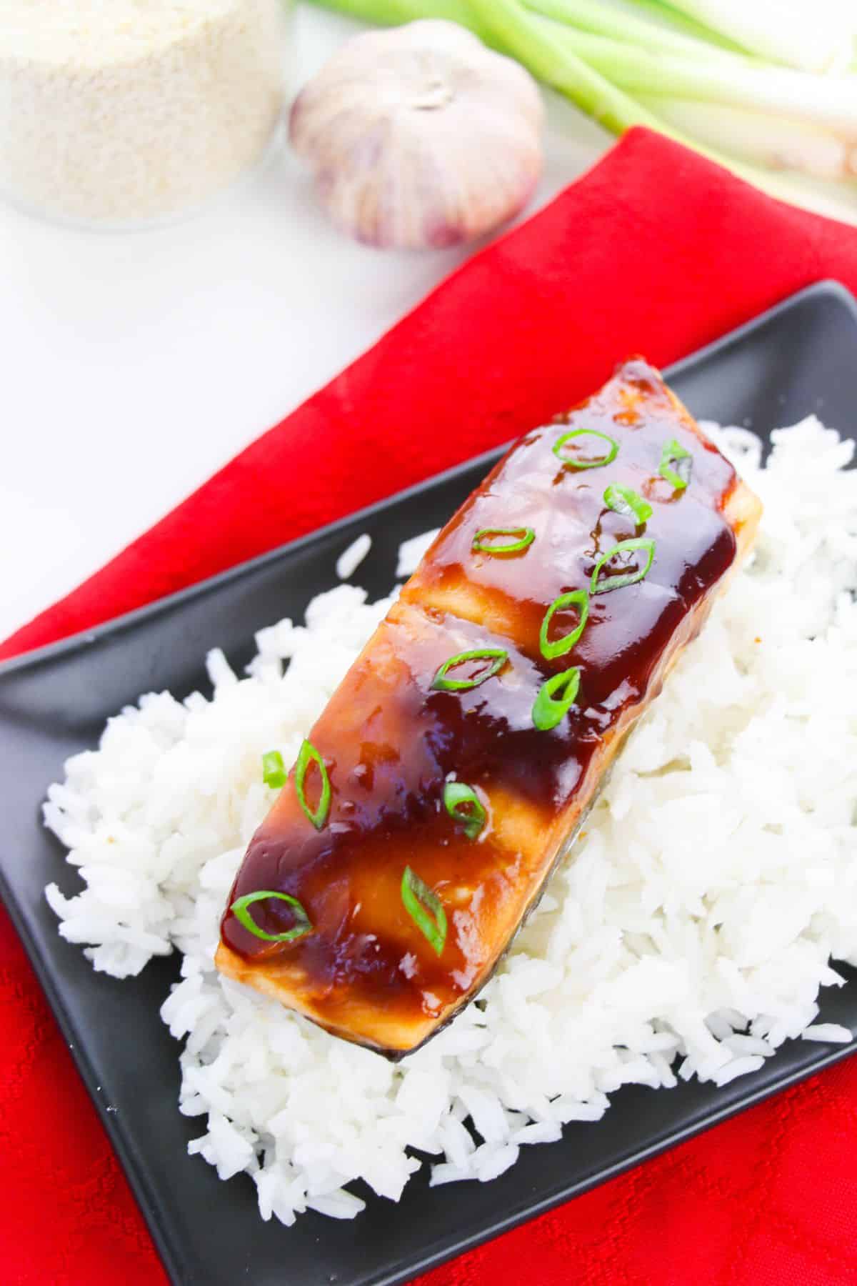 Baked Teriyaki Glazed Salmon on a serving plate garnished with sliced green onions.