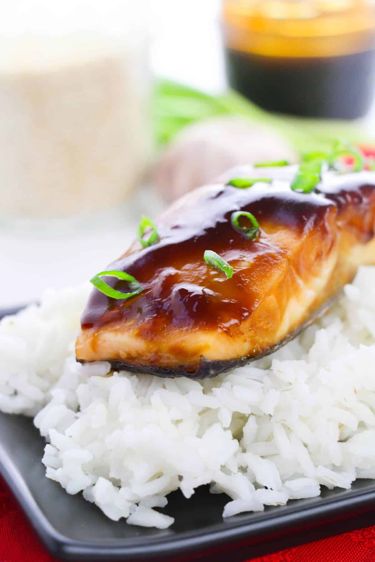 a closeup of Baked Teriyaki Glazed Salmon on a serving plate garnished with sliced green onions.