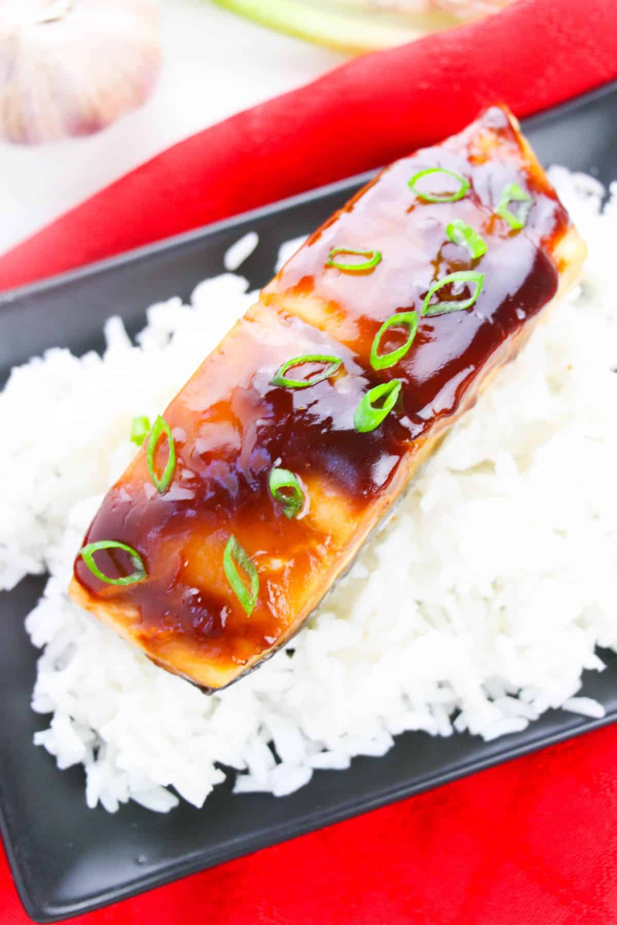 Baked Teriyaki Glazed Salmon on a serving plate garnished with sliced green onions.
