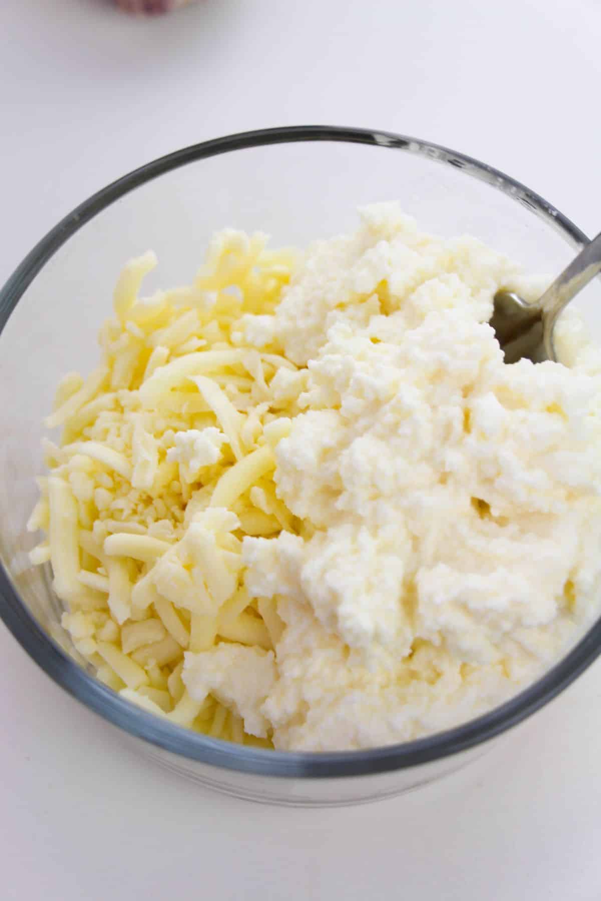Mozzarella cheese and ricotta cheese in a small mixing bowl.