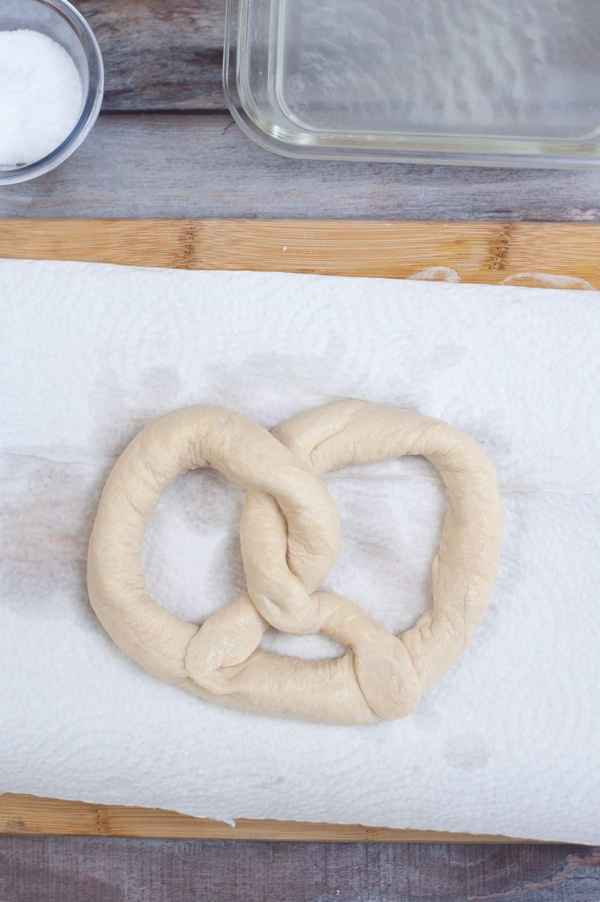 The pretzel is placed on the towel with salt and baking soda water on the side.