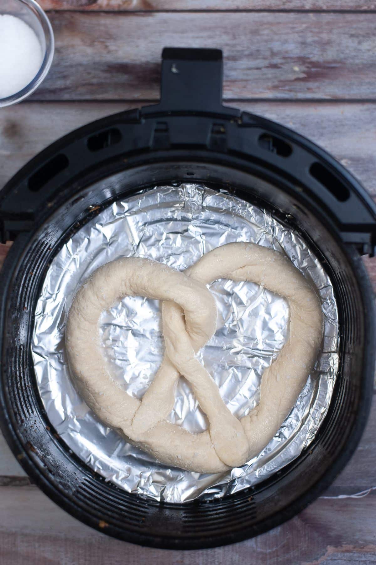 Pretzel dough with salt inside the Air Fryer with aluminum foil. 