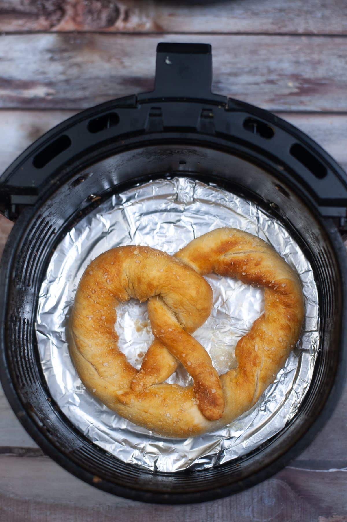 Cooked pretzel inside the Air Fryer with aluminum foil.