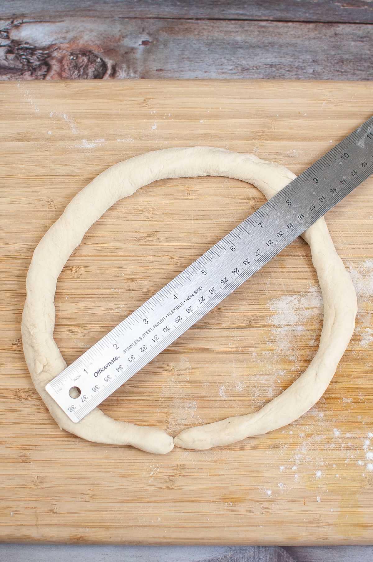 Rolled dough on a wooden chopping board with measuring ruler.