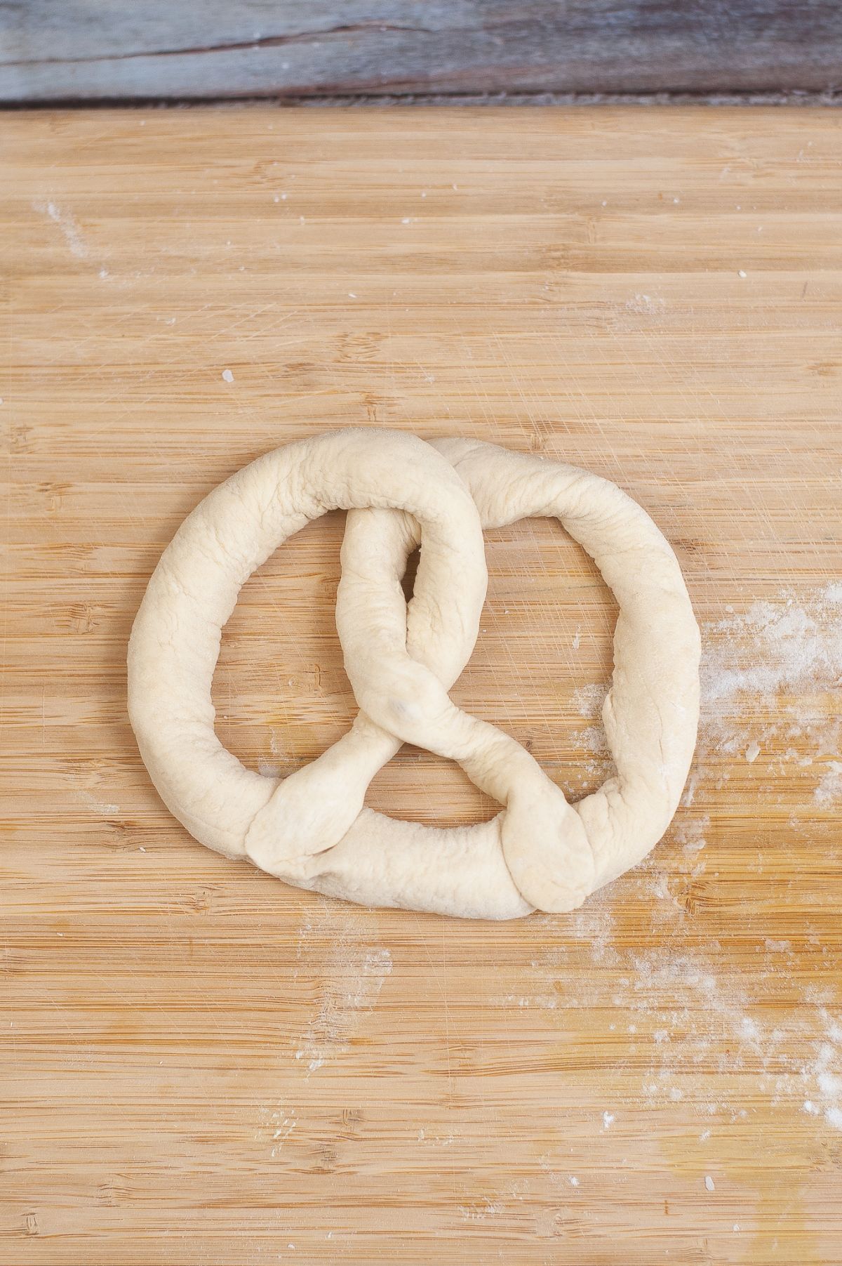 Twisted pretzel dough on the wooden chopping board.