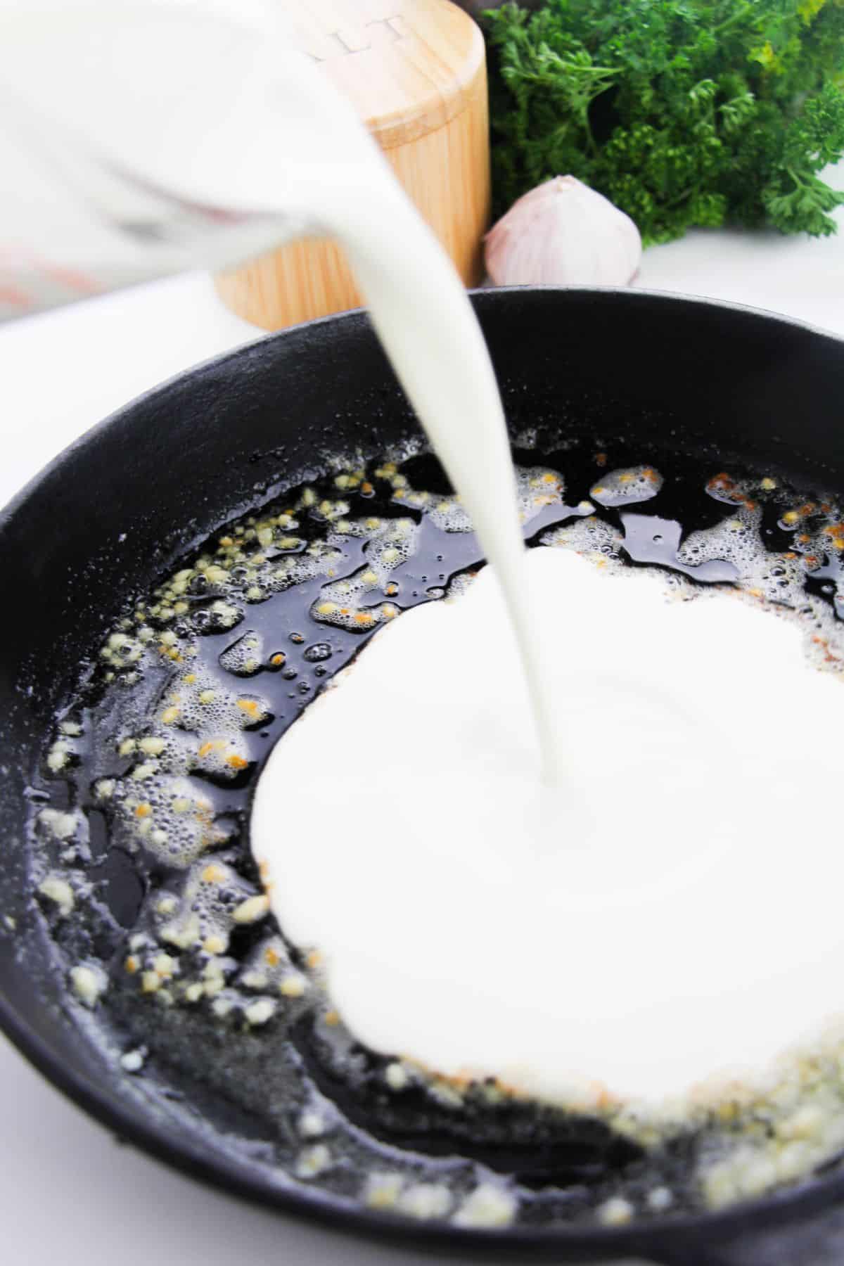 The heavy cream is added to the skillet.