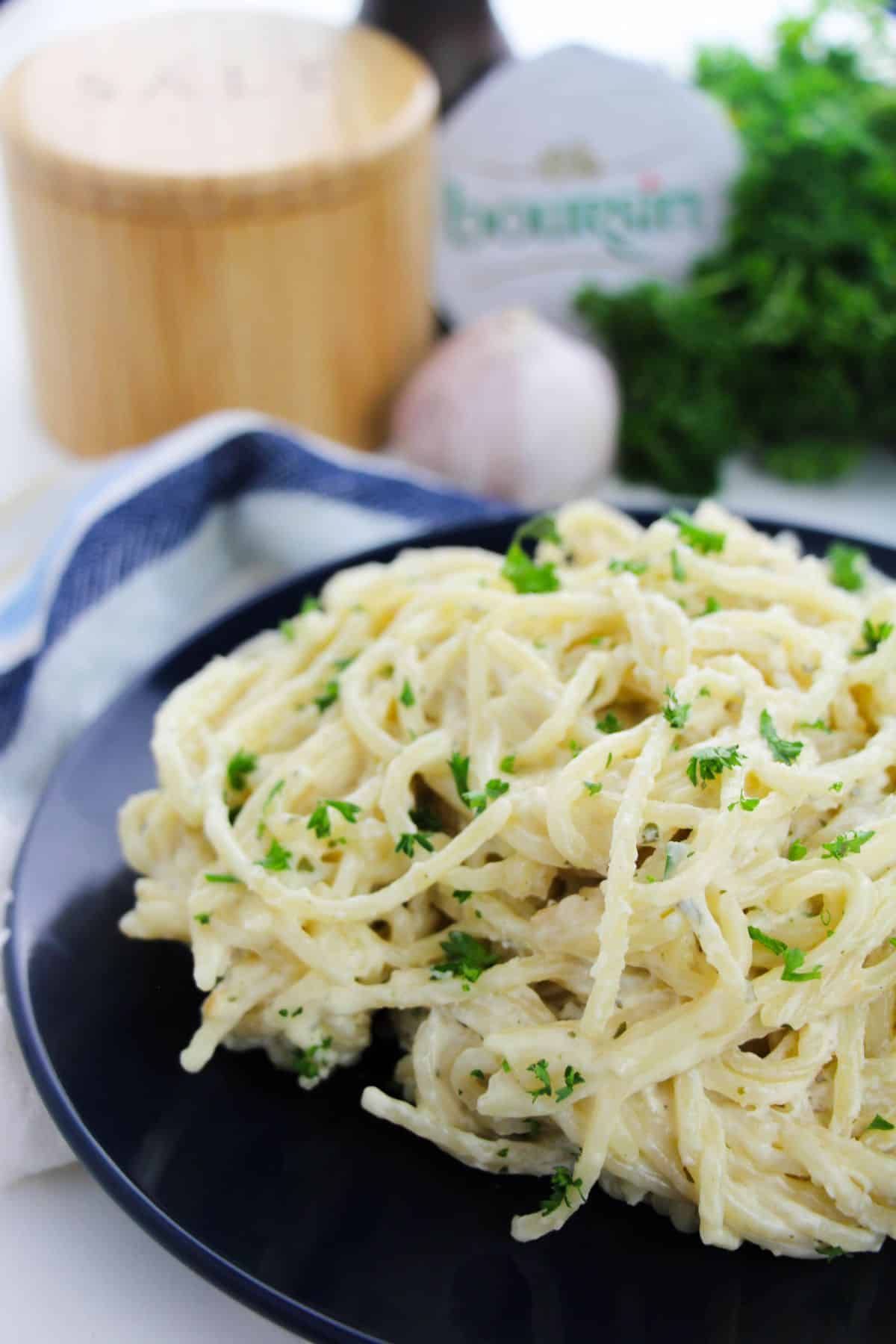 Boursin Cheese Pasta on a serving plate, garnished with parsley and ingredients on the side.
