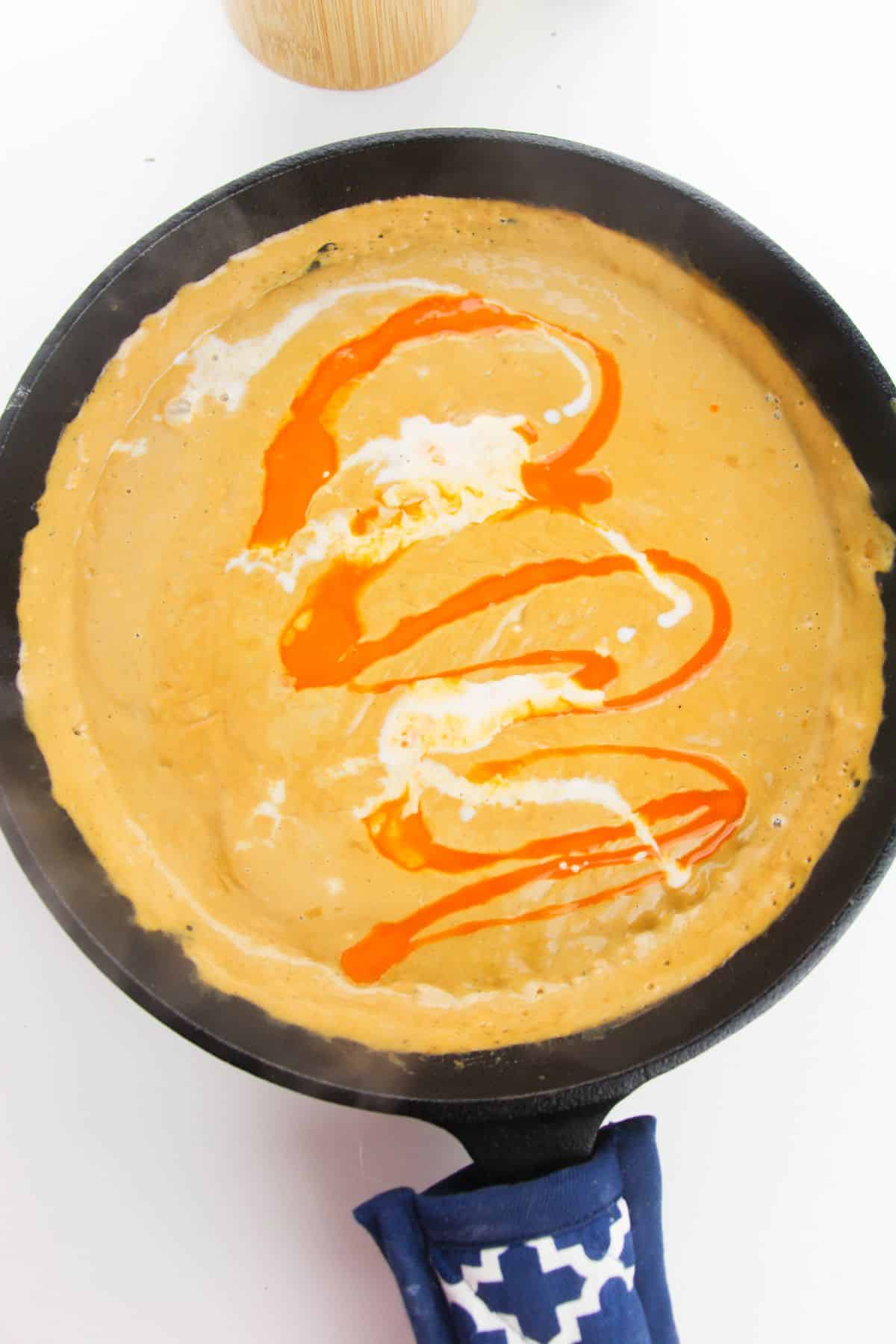 Buffalo sauce and milk are added to the  mixture in the skillet.