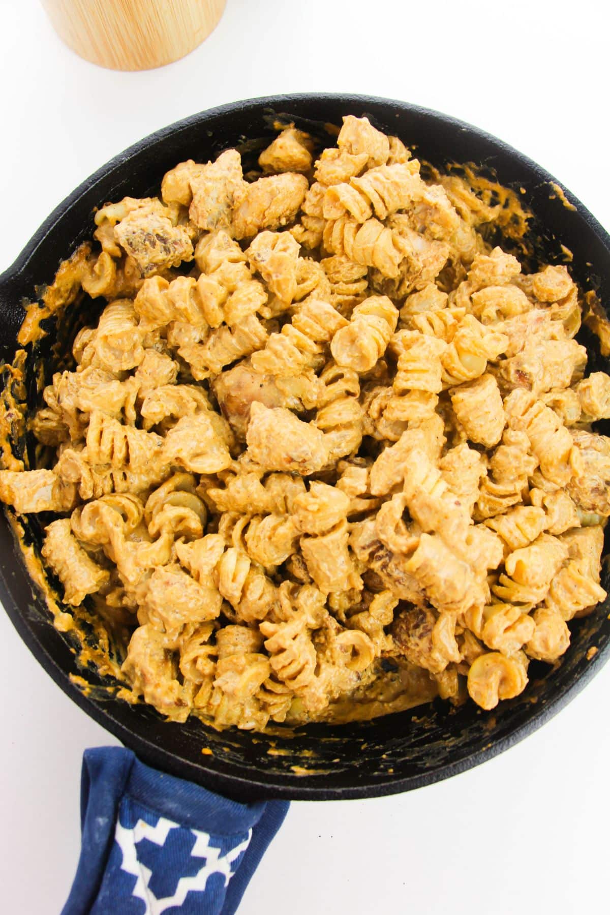 In a large skillet, chicken and pasta are being tossed together with the sauce.
