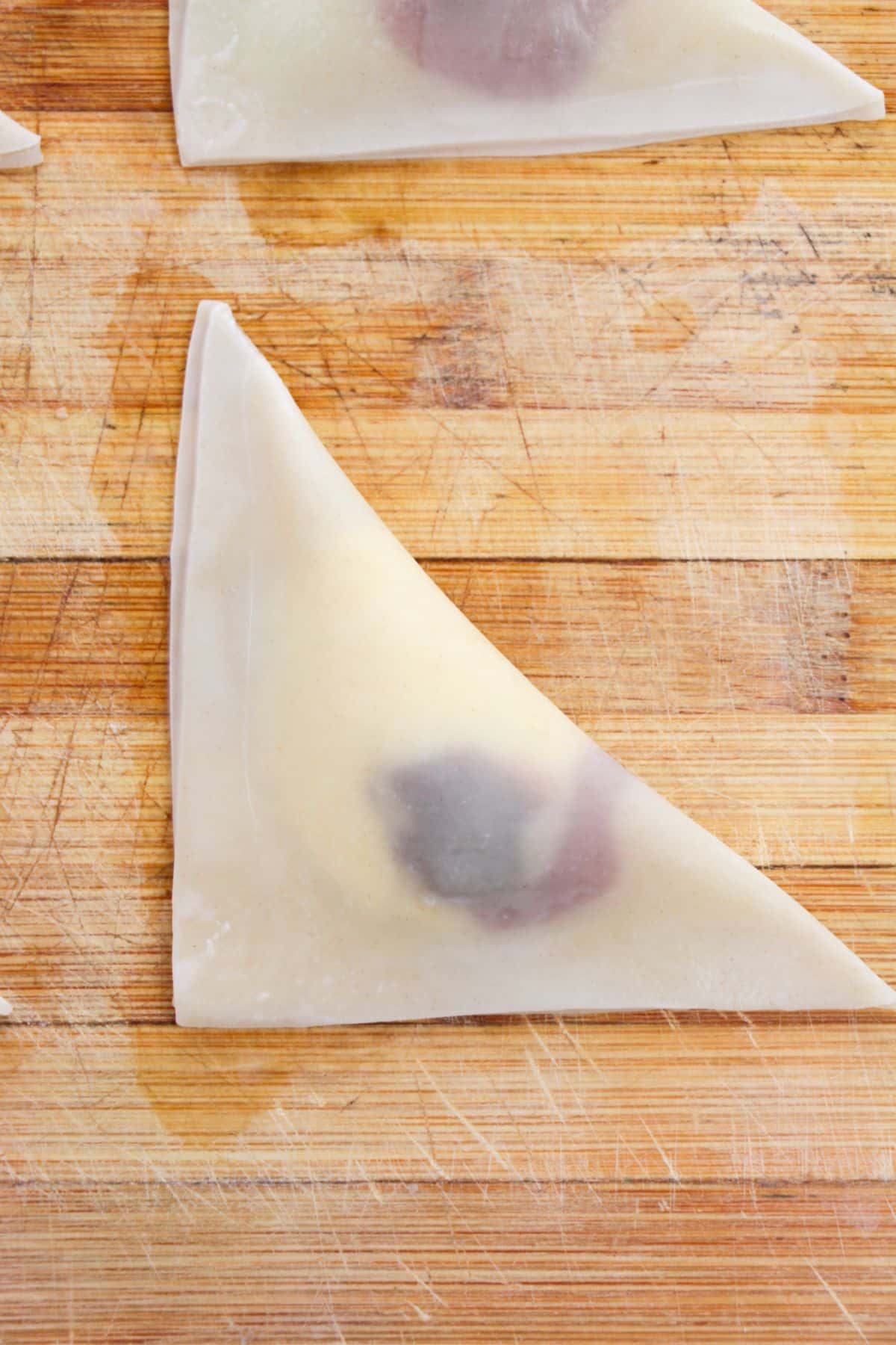 Wonton wrapper with cream cheese mixture and cherry pie filling Folded over into a triangle shape.