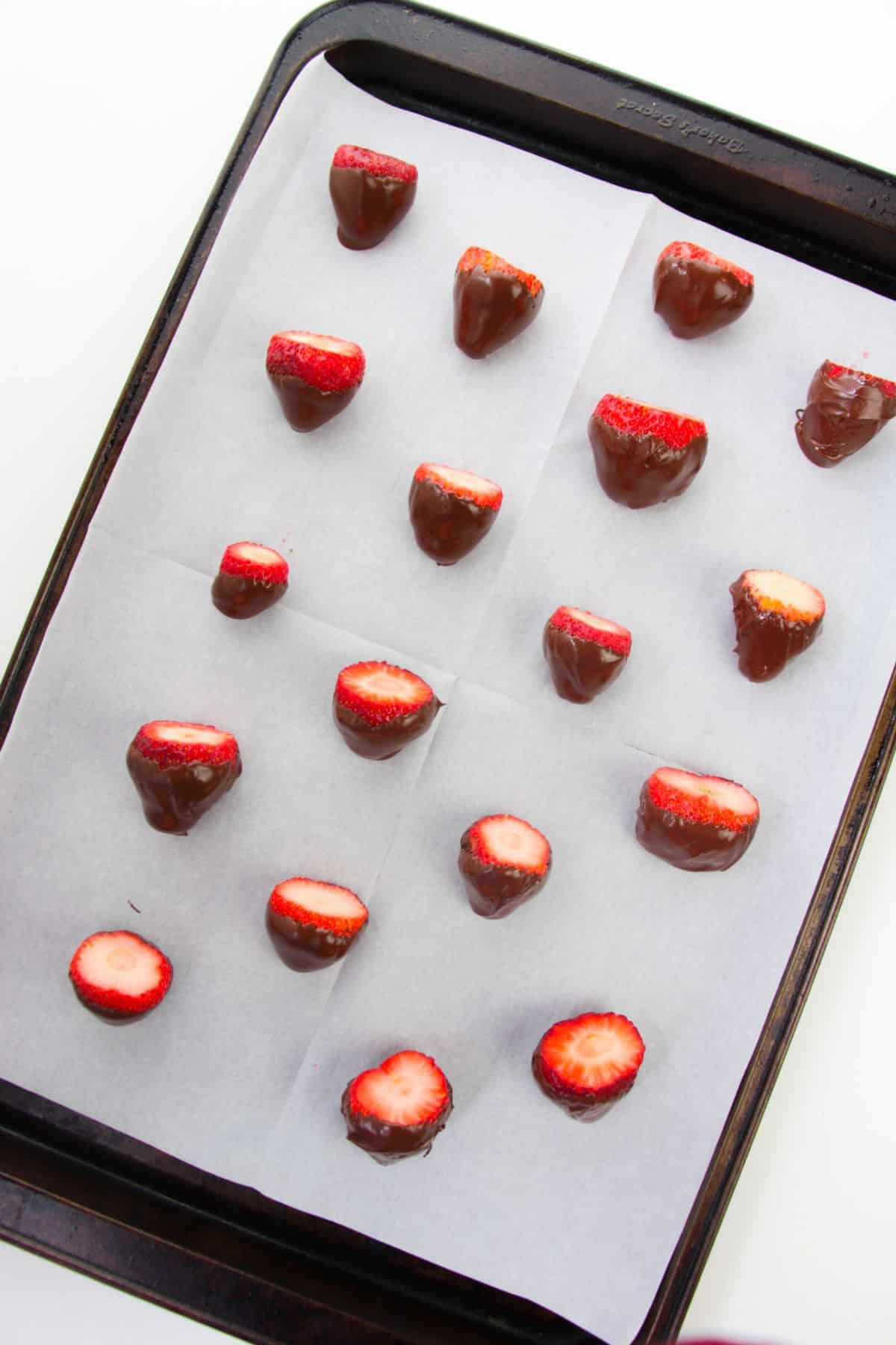 Chocolate-coated strawberries on a baking sheet.
